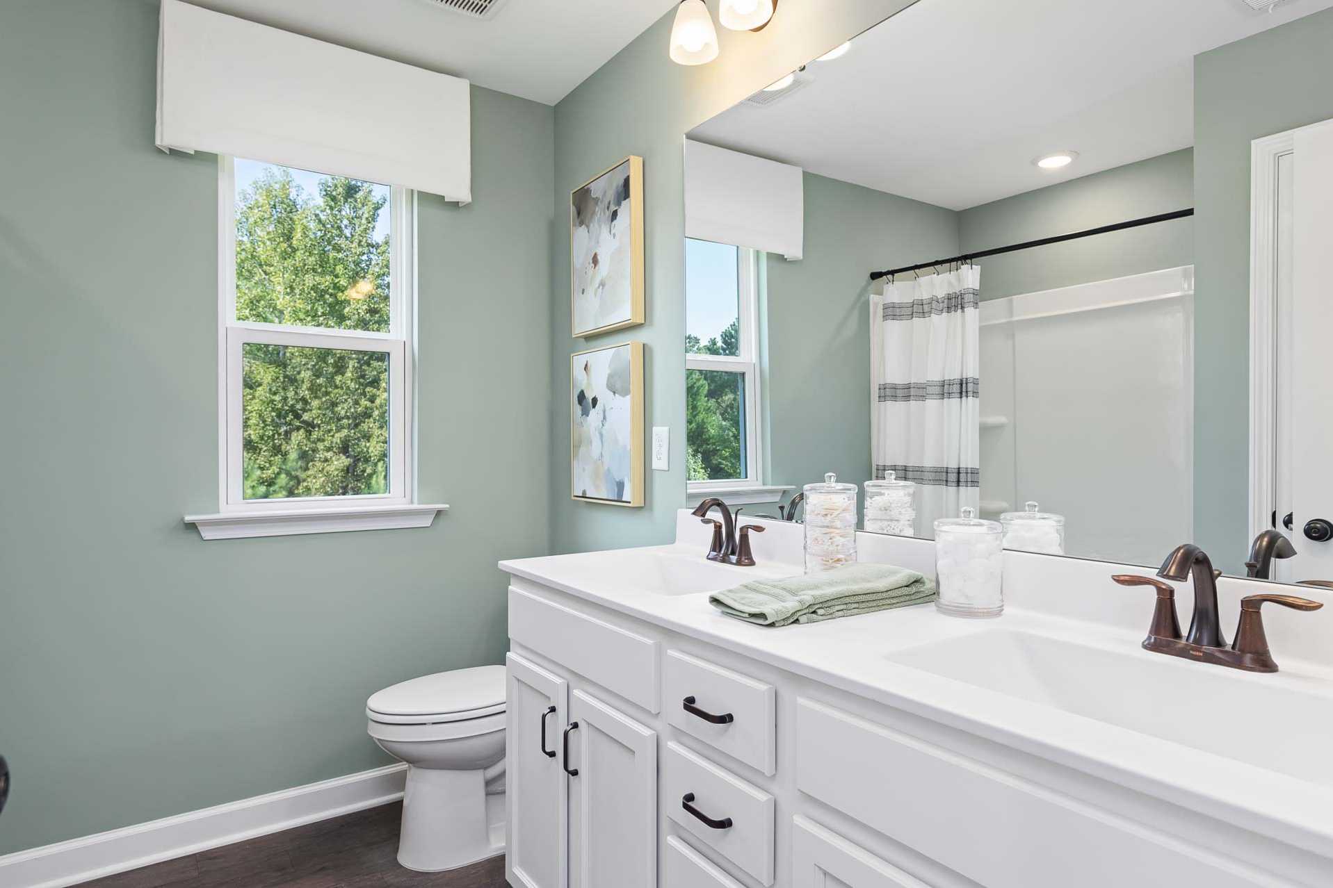 Spacious primary bathroom at Prince Place in Fuquay-Varina NC with sage walls, double vanity, and bronze fixtures
