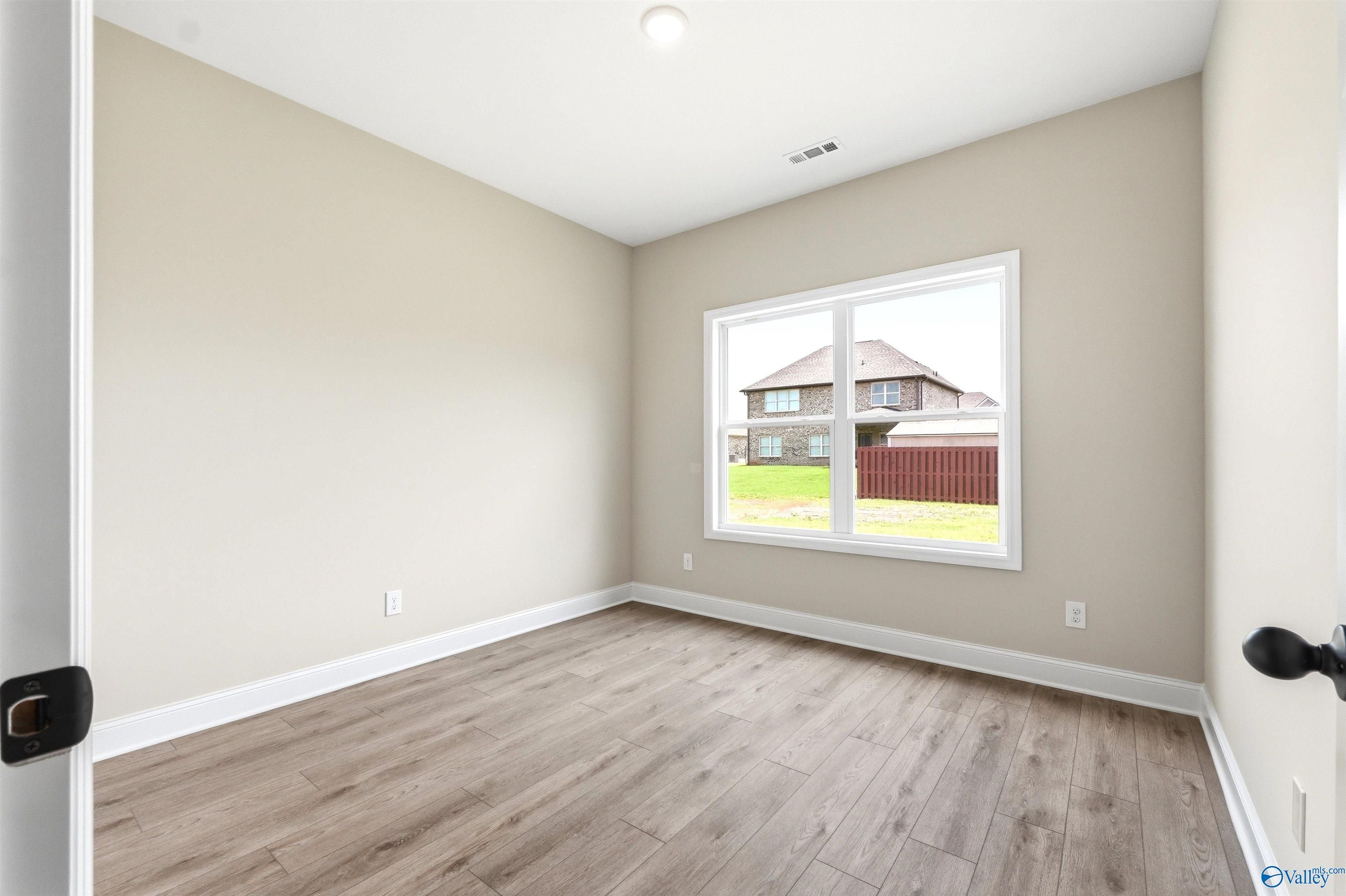 Bright, neutral-toned bedroom with wood-look flooring in The Shelby A floor plan at Wood Trail in Toney, Alabama.