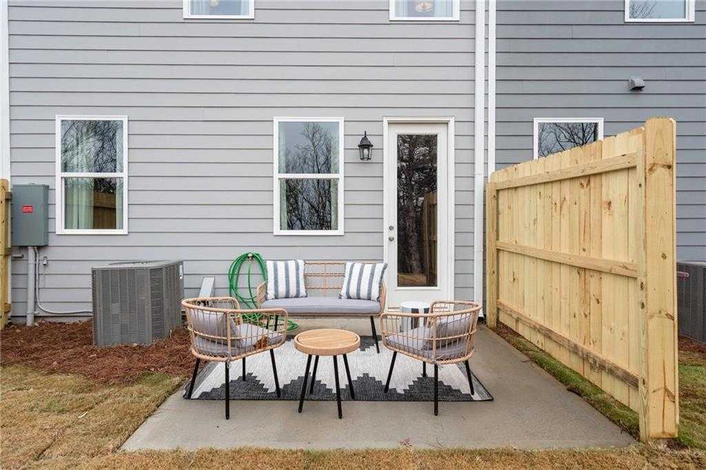 Covered back patio with wicker chairs, round table, and wooden privacy fence in Davidson Homes Wilmington B, Stegall Village, Emerson, Georgia