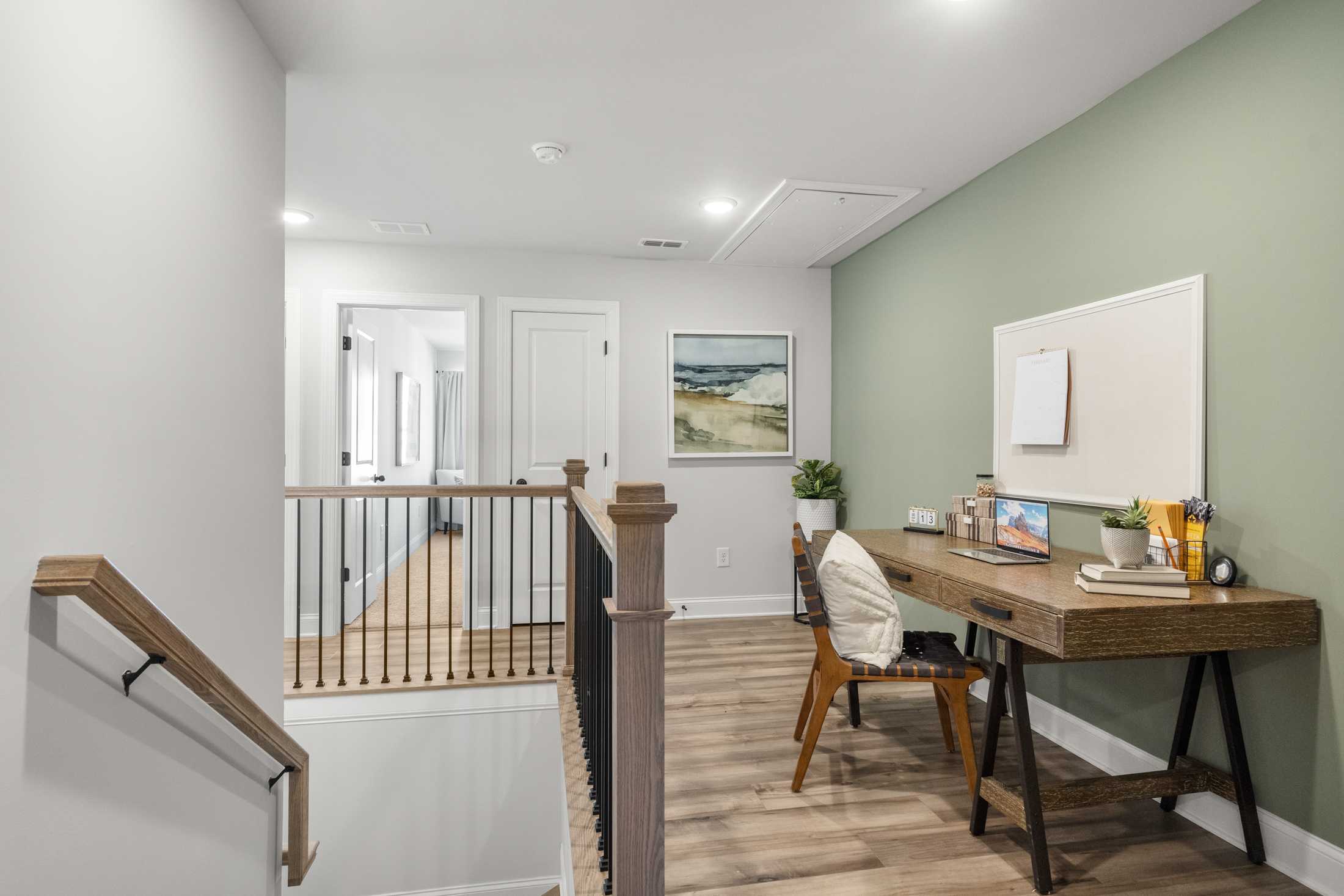 Cozy loft study nook at Rosehill Townhomes in Marietta GA with wooden desk, laptop, plants, and sage green wall