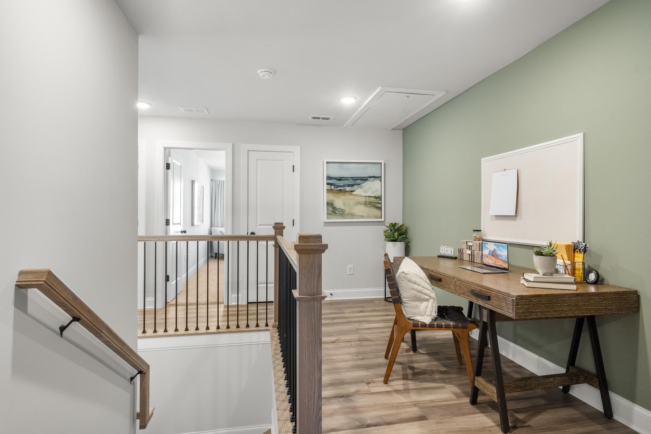 Cozy loft study nook at Rosehill Townhomes in Marietta GA with wooden desk, laptop, plants, and sage green wall