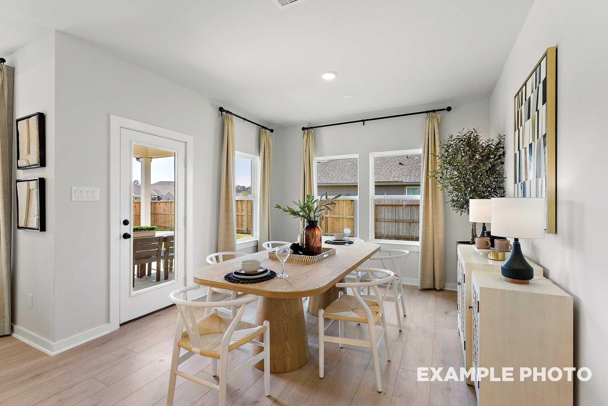 Bright dining room with wood table and modern chairs in The Everett E floor plan at Sundance Cove, Crosby, Texas.