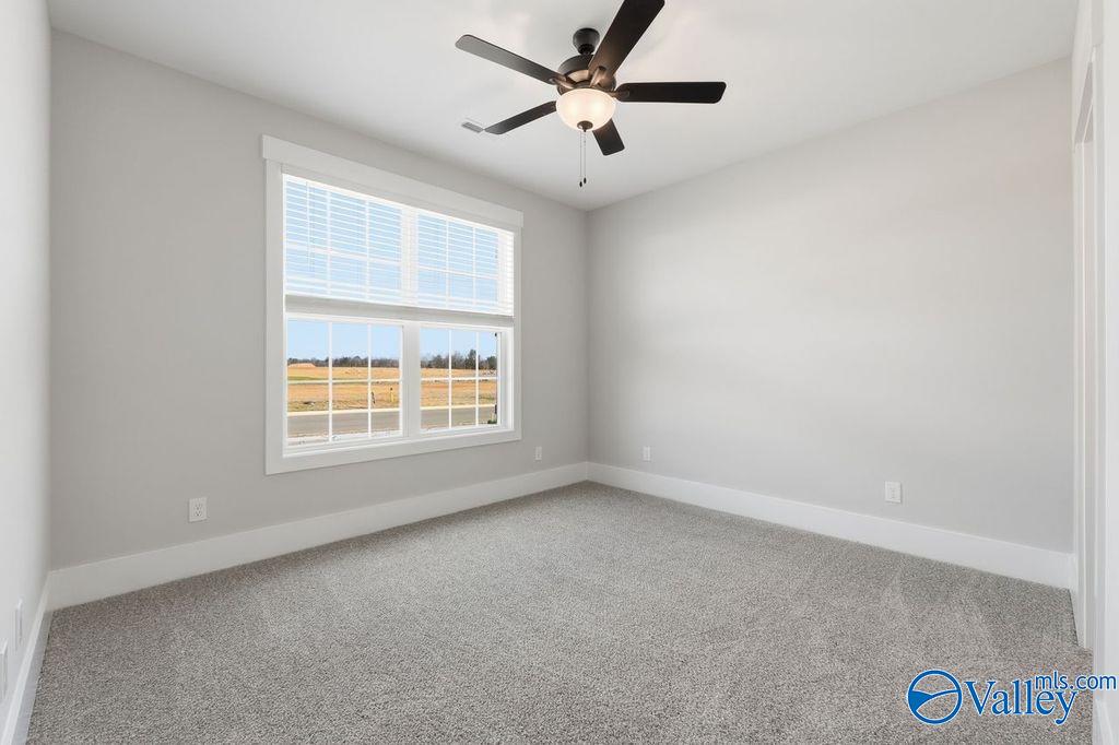 Bright bedroom with large windows overlooking fields, dual ceiling fans, gray walls in Davidson Homes The Rockford, Hartselle, Alabama