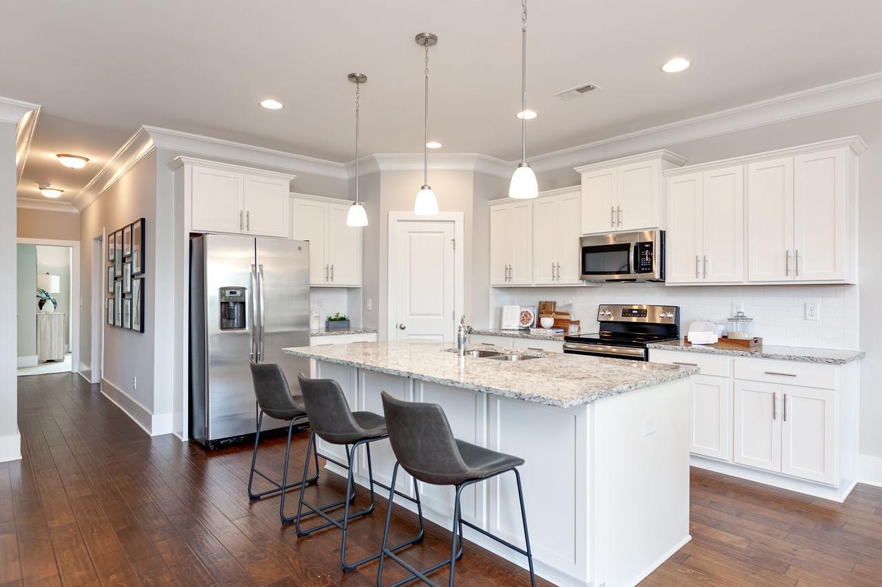 Spacious white shaker kitchen in The Rockford with large quartz island, stainless steel appliances, pendant lights, and bar stools