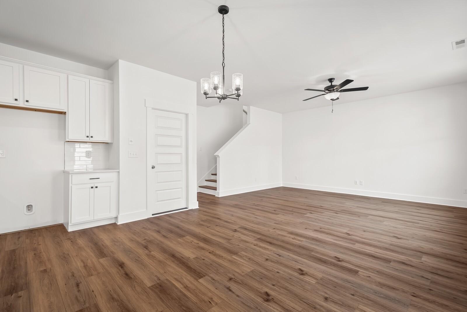 Open entryway with white cabinets, staircase, chandelier, ceiling fan, and hardwood floors in Davidson Homes The Logan C, Gallatin, TN