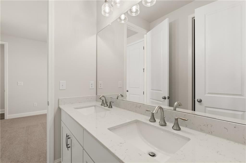 Modern double vanity with white quartz countertop, chrome faucets, and large mirror in master bath of Davidson Homes The Danbury C, Buford, GA