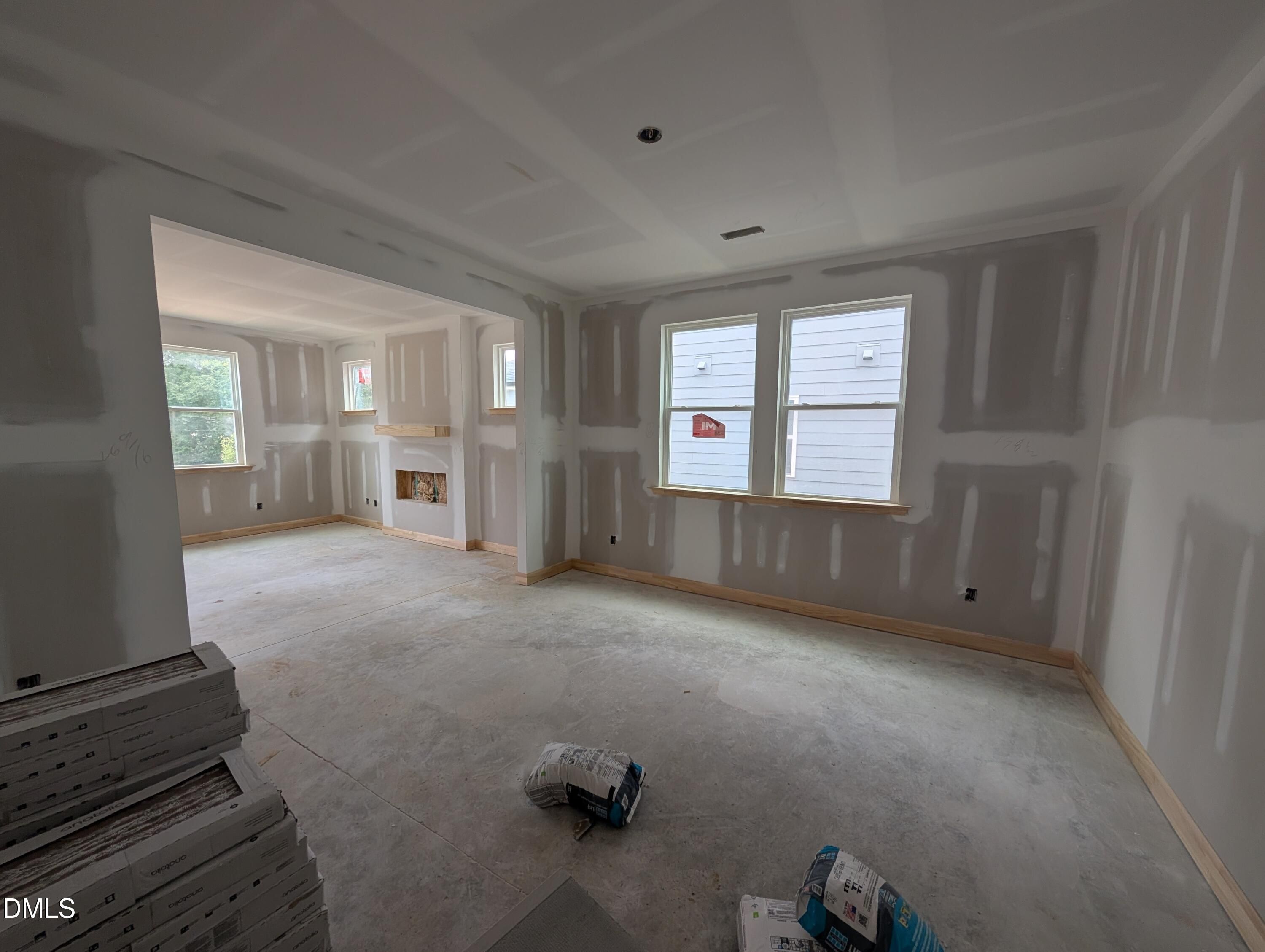 Unfinished open-concept living room under construction with fireplace and coffered ceiling in Davidson Homes The Beech floor plan, Wendell NC