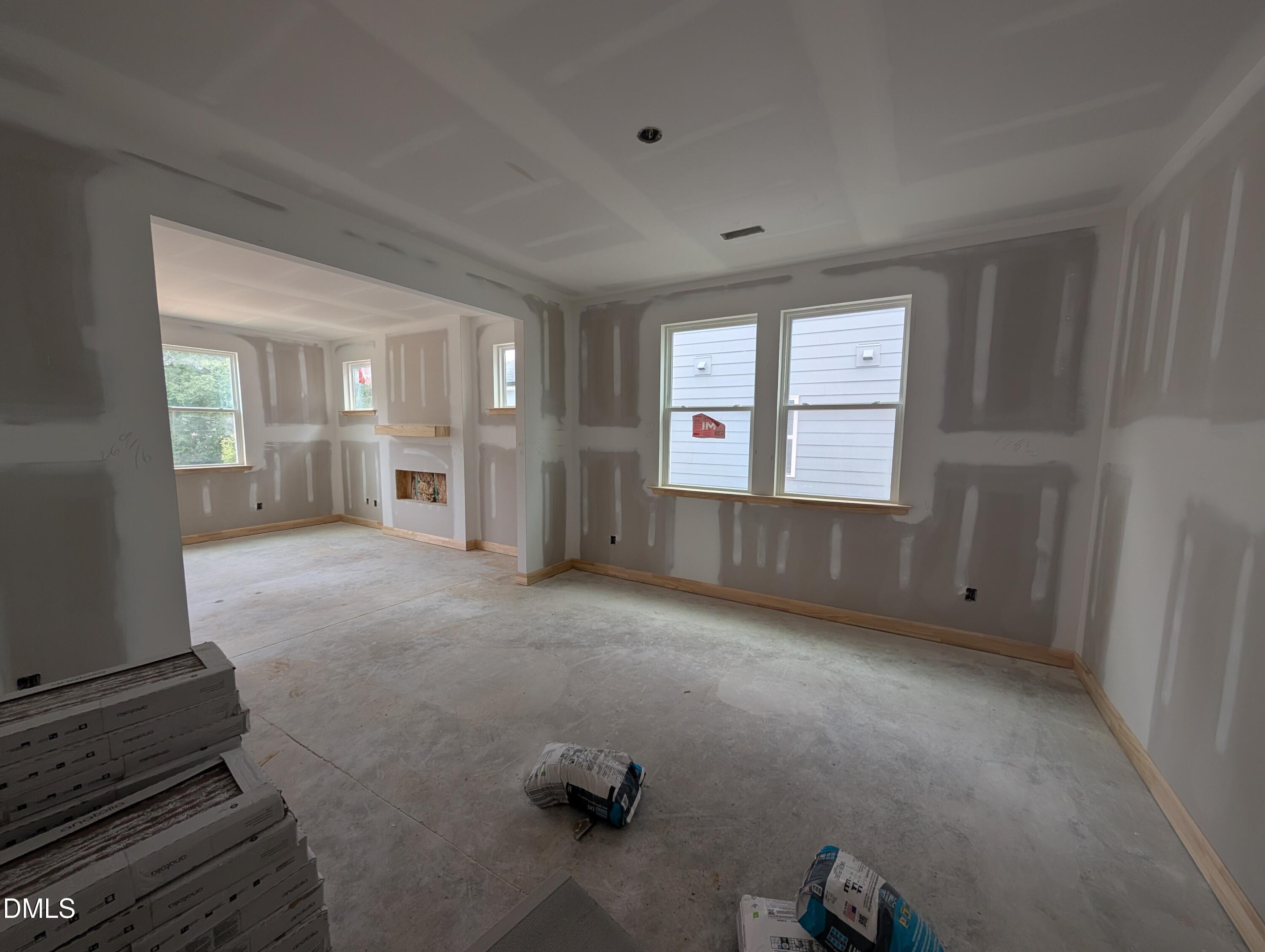 Unfinished open-concept living room under construction with fireplace and coffered ceiling in Davidson Homes The Beech floor plan, Wendell NC
