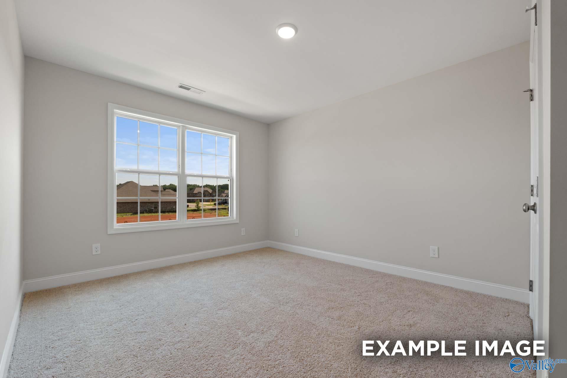 Bright empty bedroom with large window overlooking neighborhood in The Madison A 5-bedroom home, Toney, Alabama