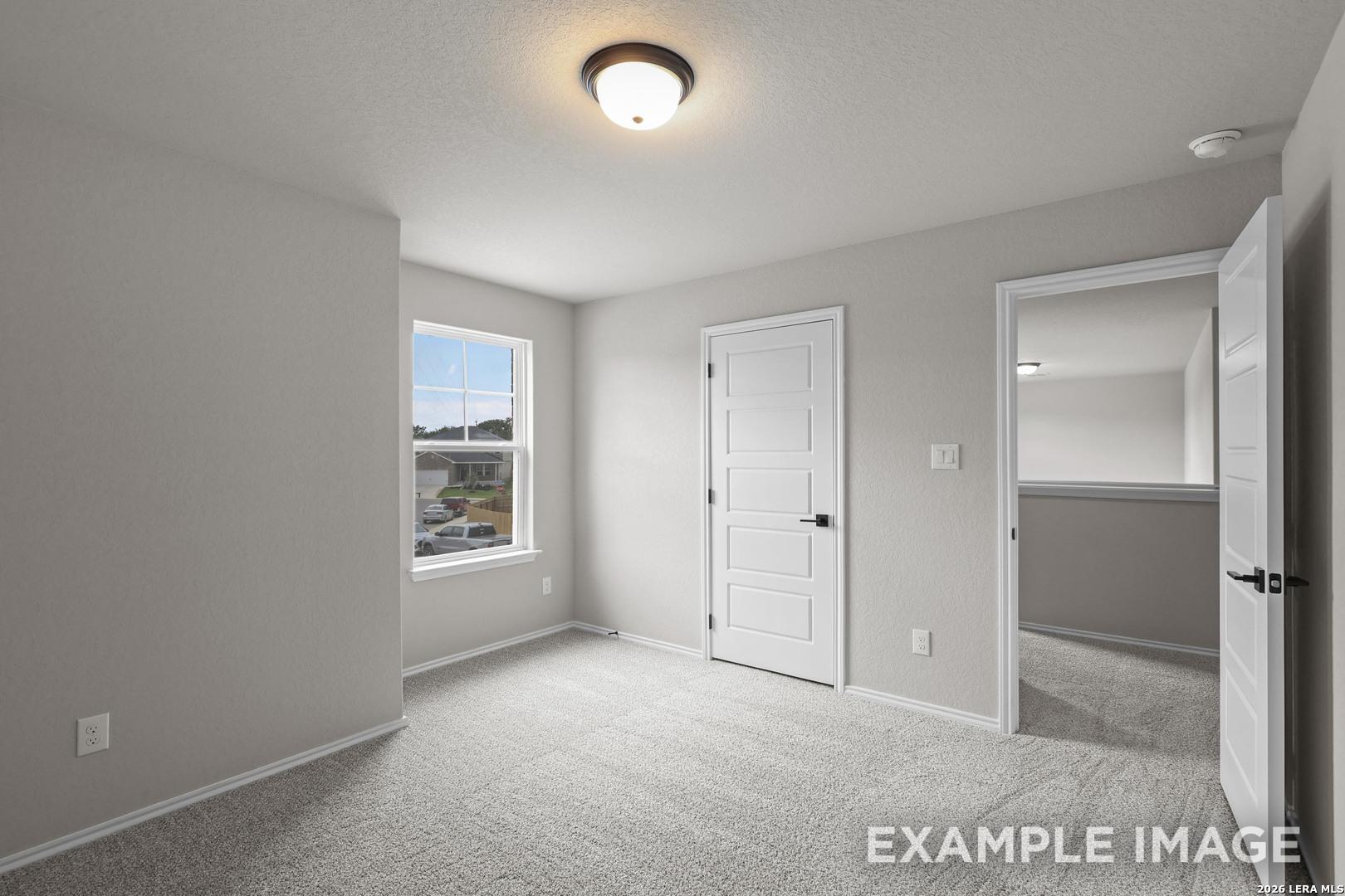 Bright neutral bedroom with carpet and white panel doors in Davidson Homes The Murray H plan at Horizon Pointe, Converse, Texas
