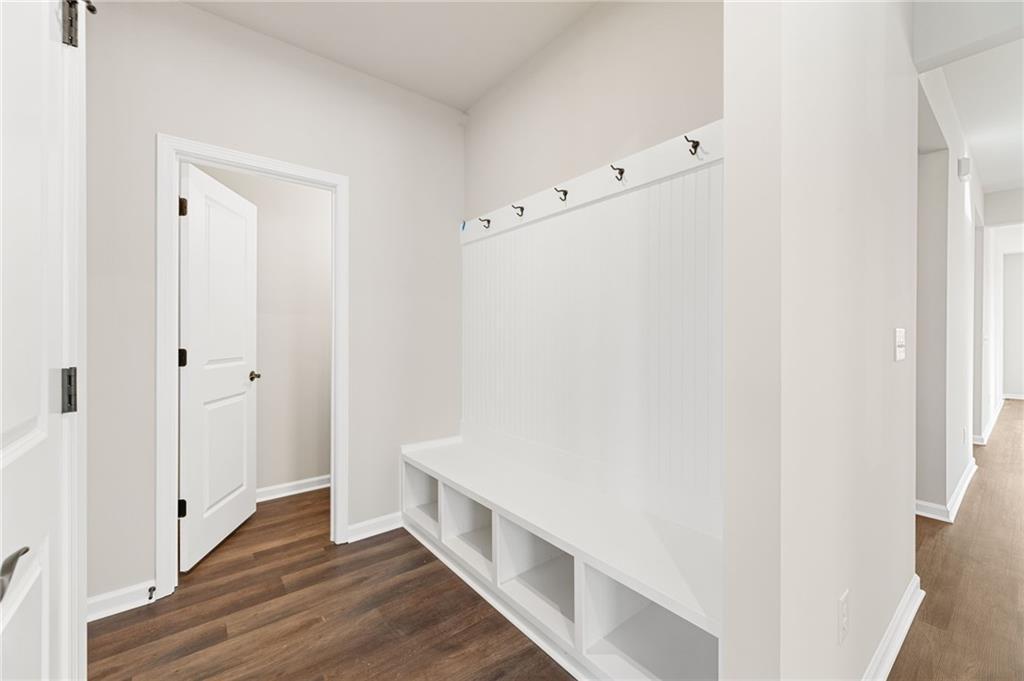 White mudroom featuring coat hooks, built-in bench, and open shelves in Davidson Homes The Glenwood A, Loganville, Georgia