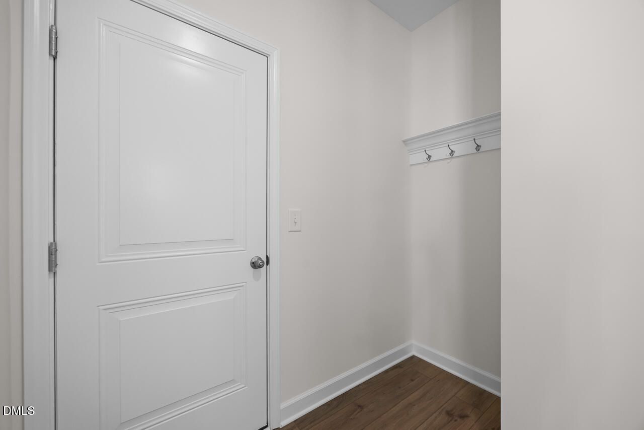 Mudroom entry with white paneled door, coat hook rack, and hardwood-style flooring in Davidson Homes Willow B plan, Zebulon NC