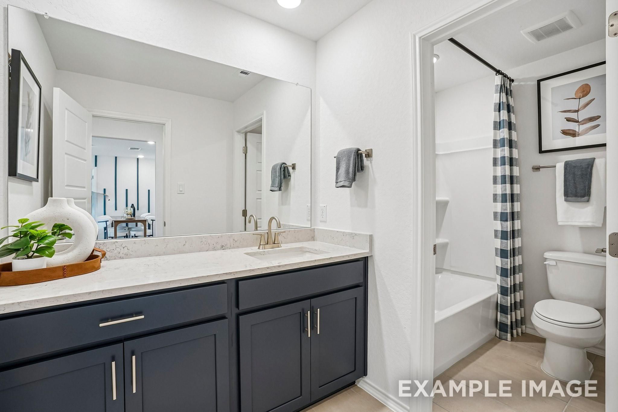 Modern bathroom with navy vanity, quartz countertop, and tub shower in Davidson Homes Ashport J plan, Sundance Cove, Crosby TX