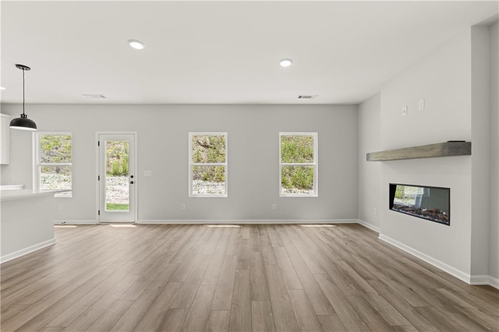 Open-concept living room with modern linear fireplace in The Hartwell A floor plan at The Bluffs in Canton, Georgia.