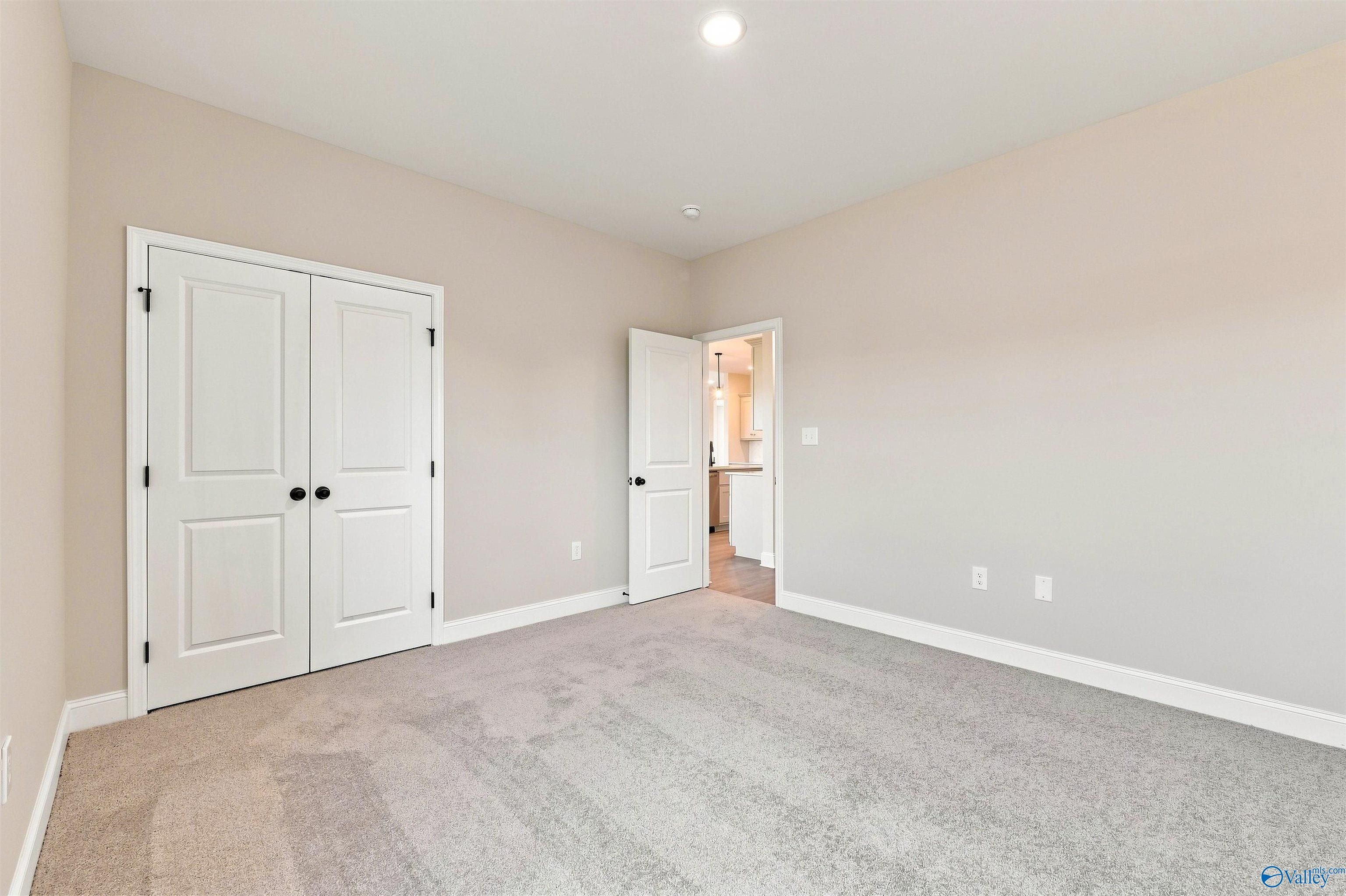 Spacious bedroom with plush carpeting, double-door closet, and view into the home in The Oxford plan, Kendall Farms, Toney.