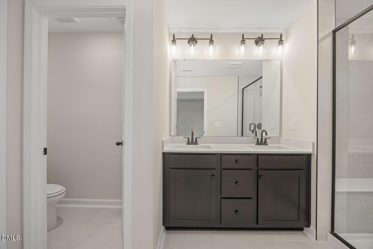 Modern master bathroom with double vanity, dark shaker cabinets, frameless glass shower in Davidson Homes The Mitchell, Knightdale NC