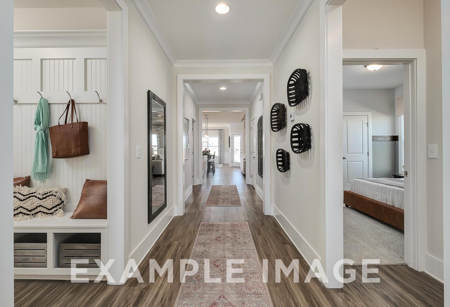 Spacious hallway in The Everett home design by Davidson Homes with white walls, wood floors, runner rug, coat hooks, and mirror
