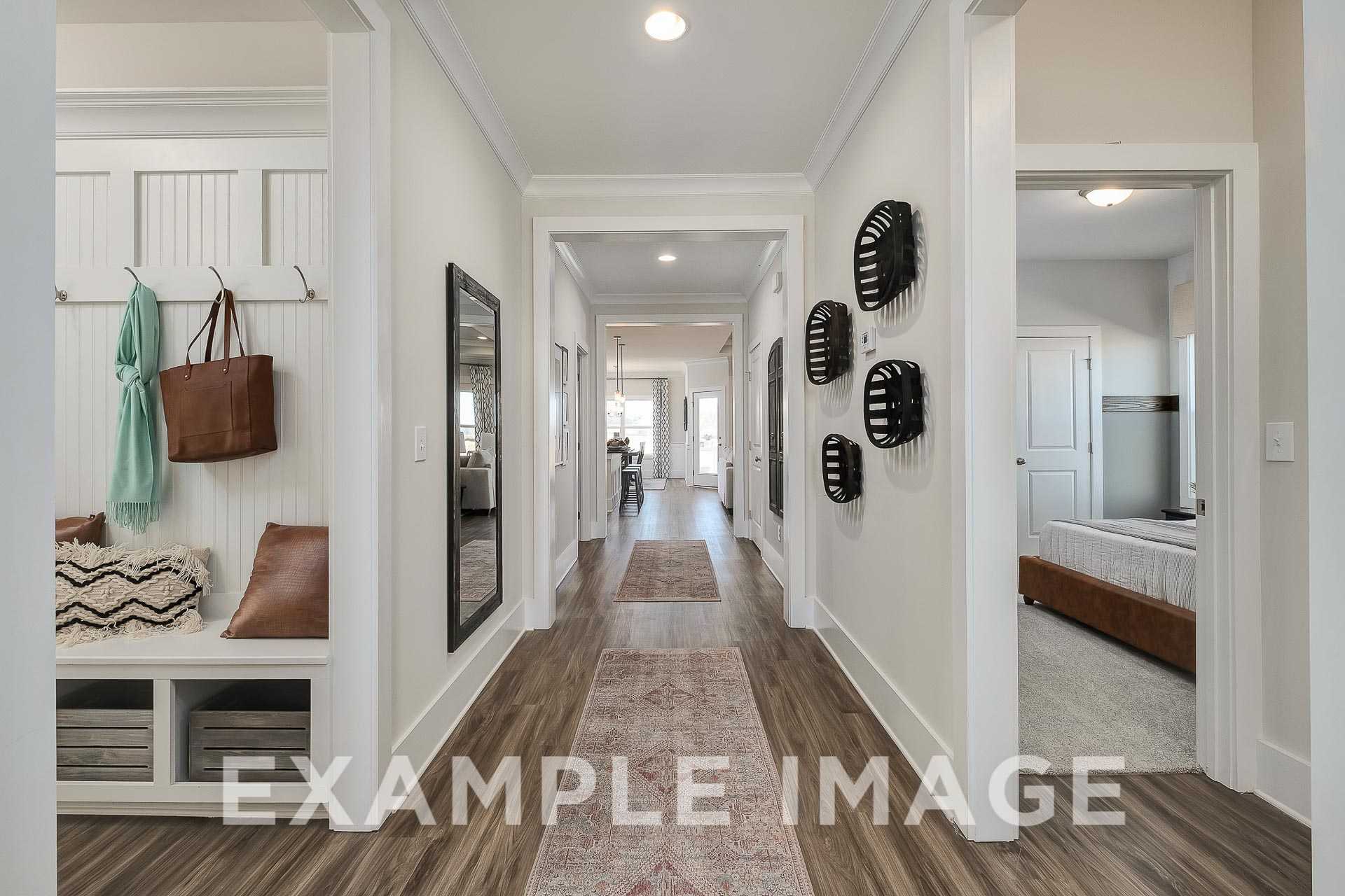 Spacious hallway in The Everett home design by Davidson Homes with white walls, wood floors, runner rug, coat hooks, and mirror