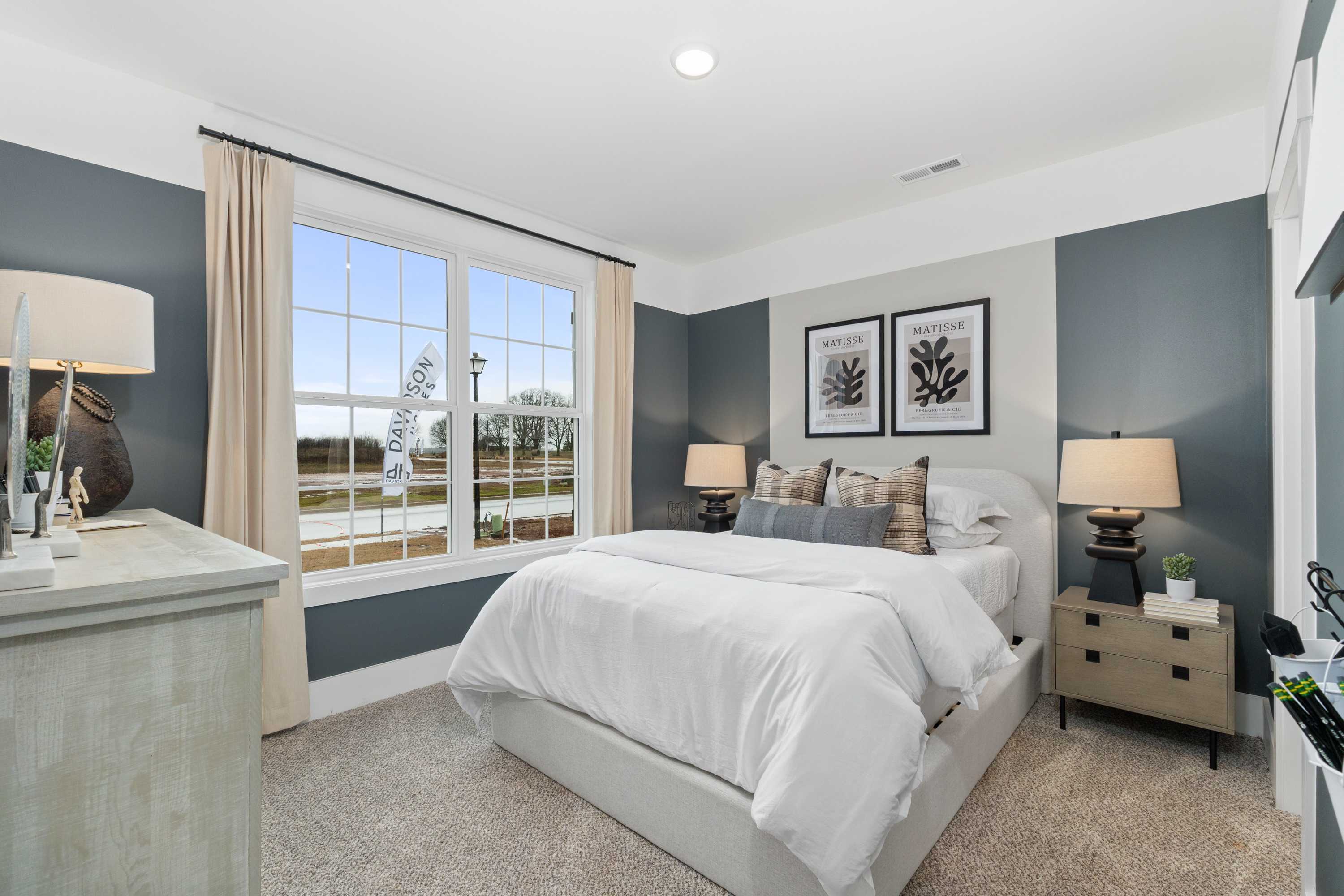 Spacious bedroom at Kendall Farms in Toney Alabama with platform bed, blue accent wall, large window view and plaid pillows