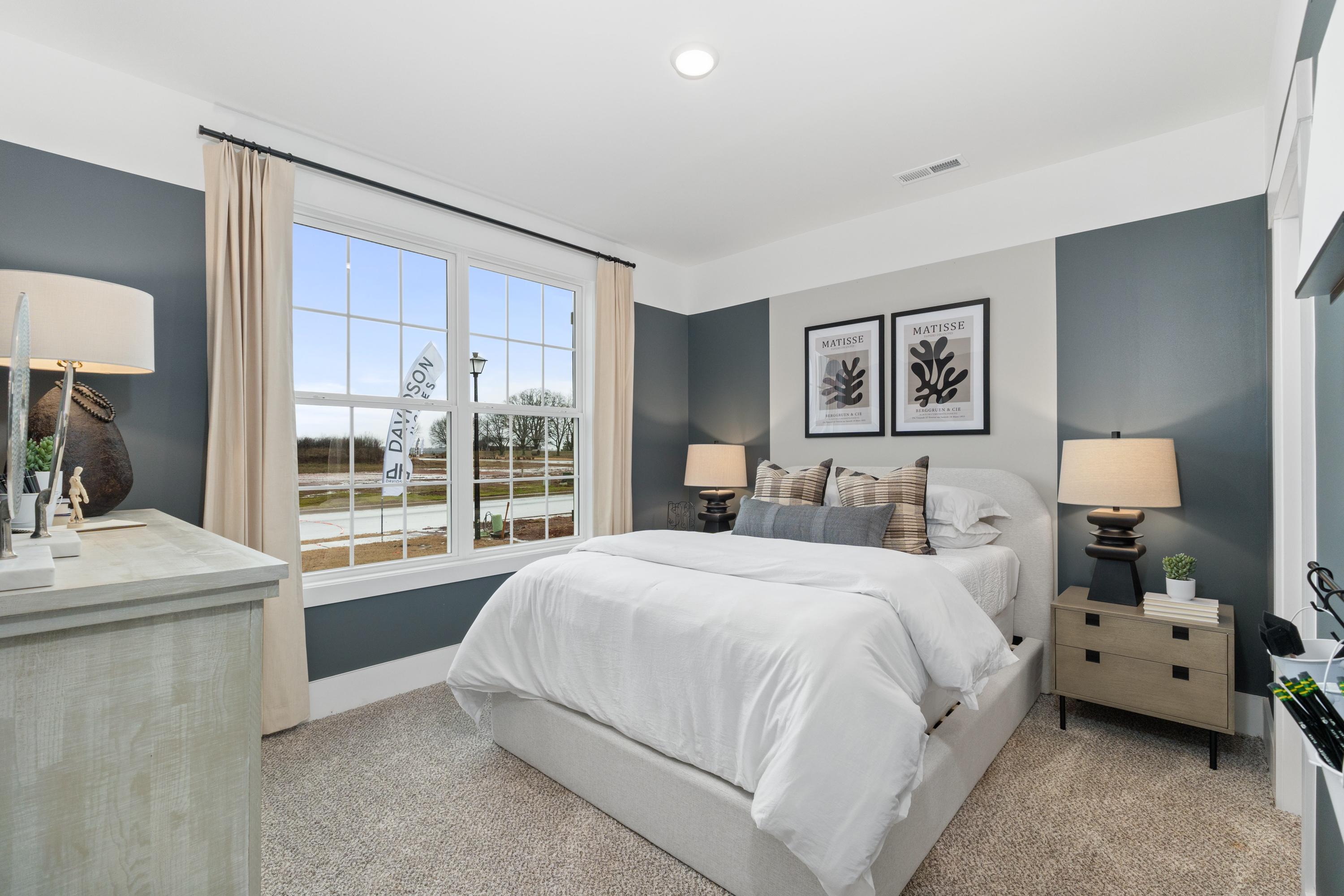 Cozy bedroom at Little Creek in Arab Alabama with navy accent wall, large window view, plush white bedding and fern art
