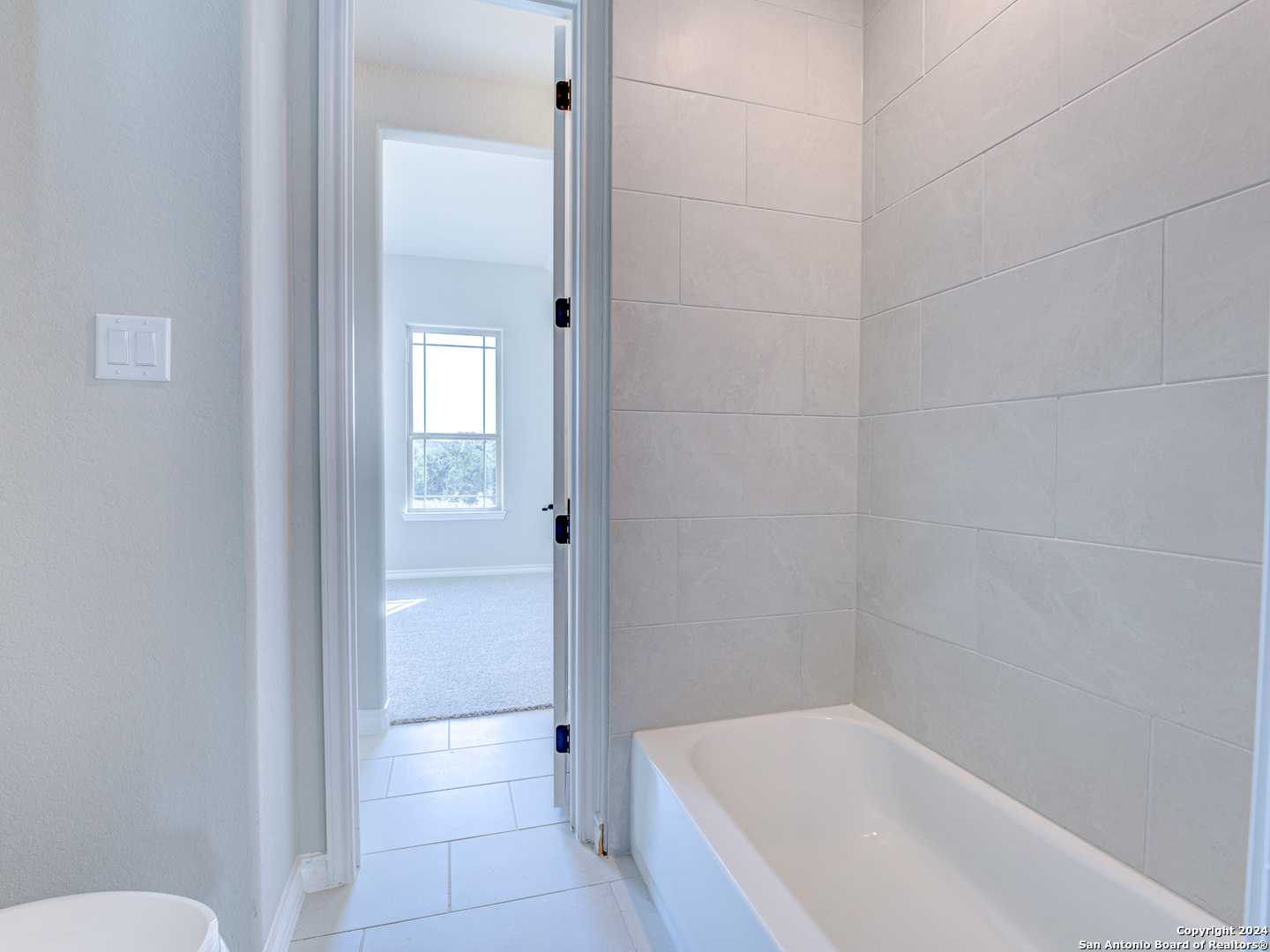 Modern bathroom with white subway tile walls and soaking tub in Davidson Homes Summerlin A, Castroville Texas