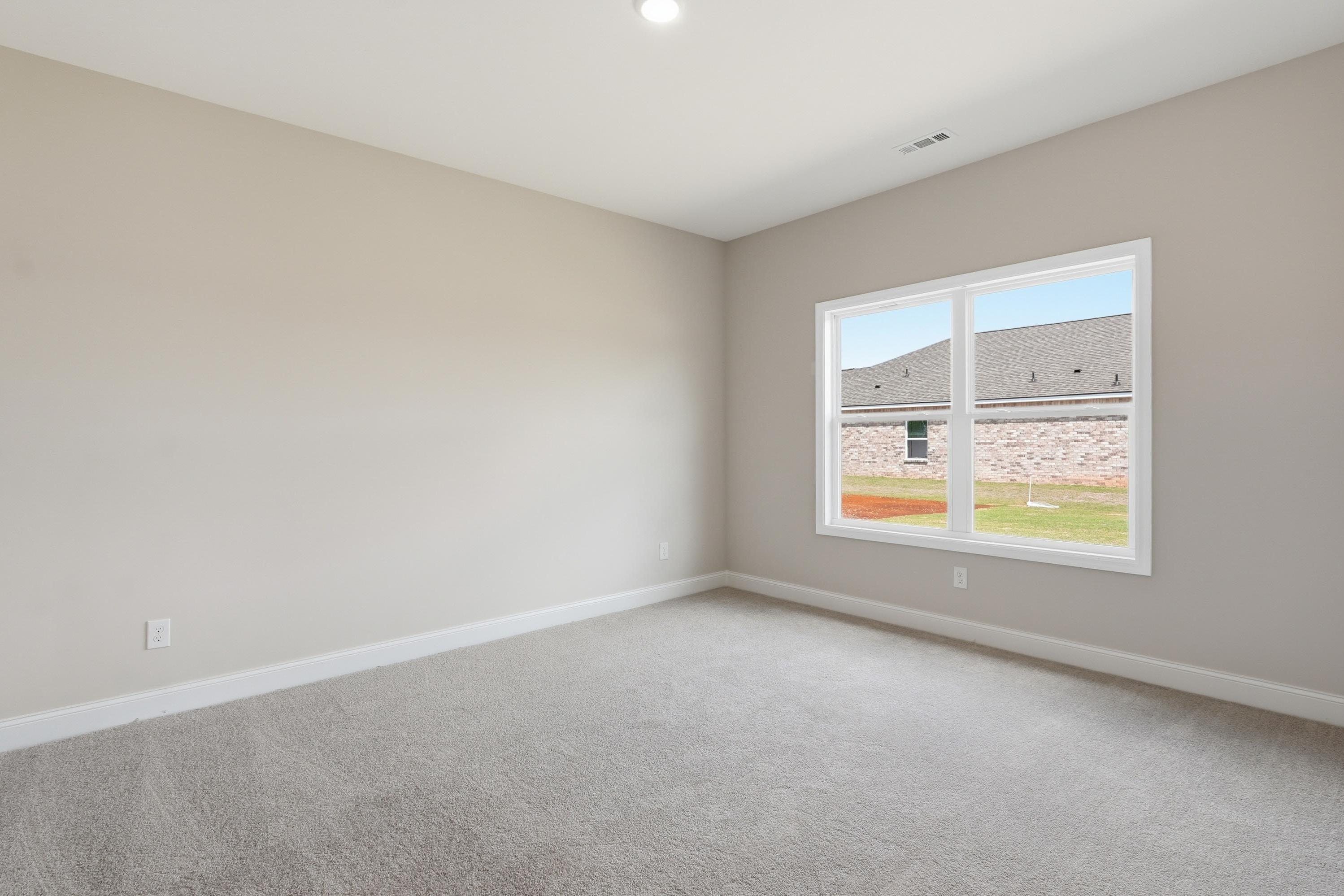 Spacious bedroom with neutral carpet and walls in The Glen A floor plan by Davidson Homes in Josephine, Texas.