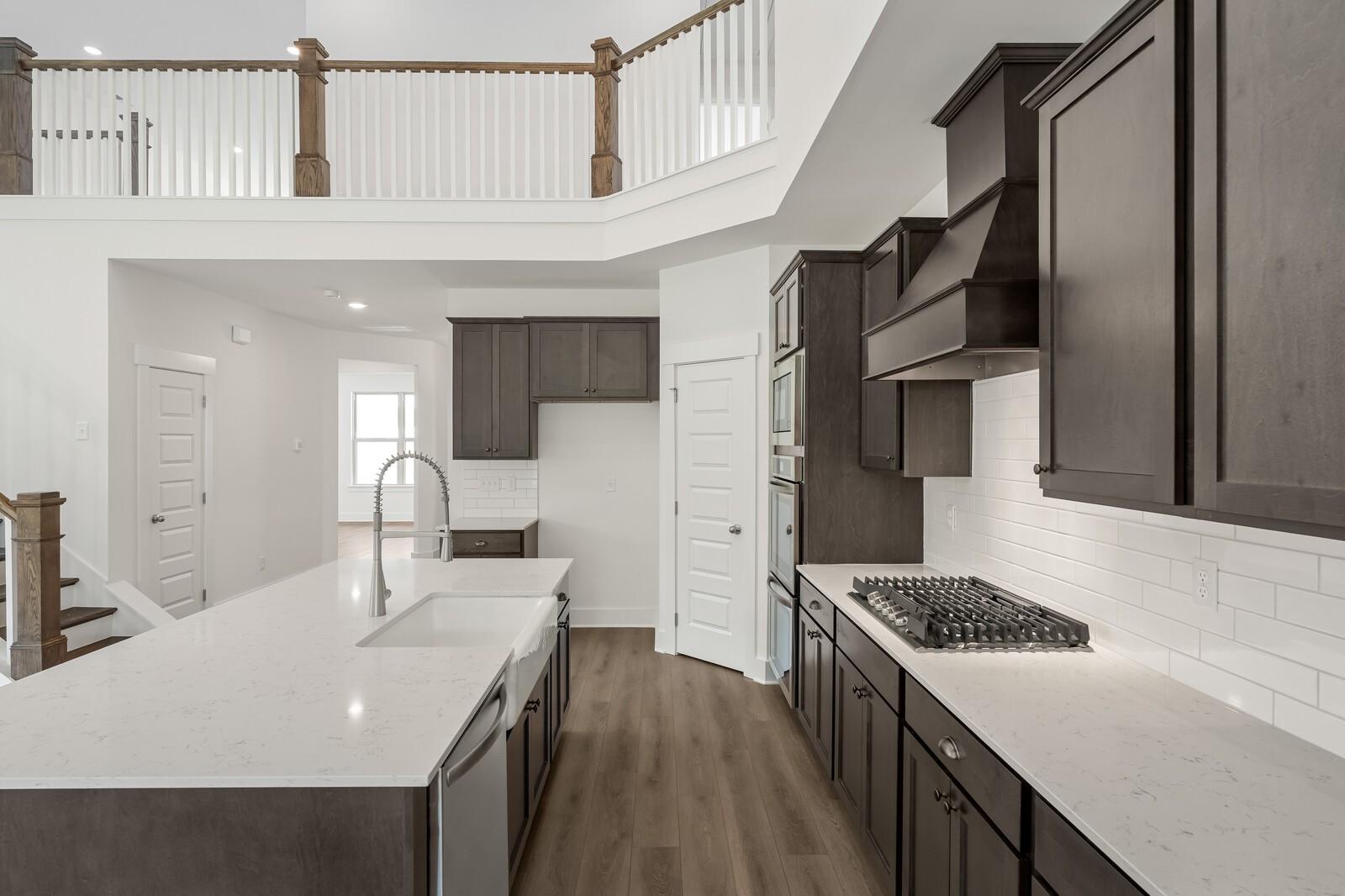 Modern kitchen with quartz island and dark cabinetry in The Ridgeport C floor plan at Woods Crossing in Gallatin, TN.
