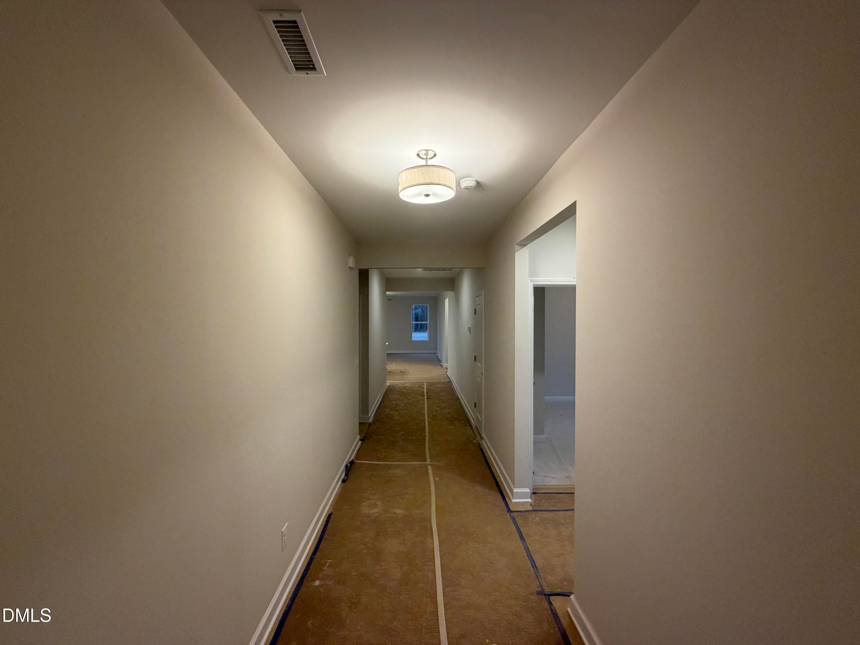 Long hallway with beige walls, pendant lighting, and plywood subfloor in The Daphne C floor plan, Wellers Knoll, Lillington, NC