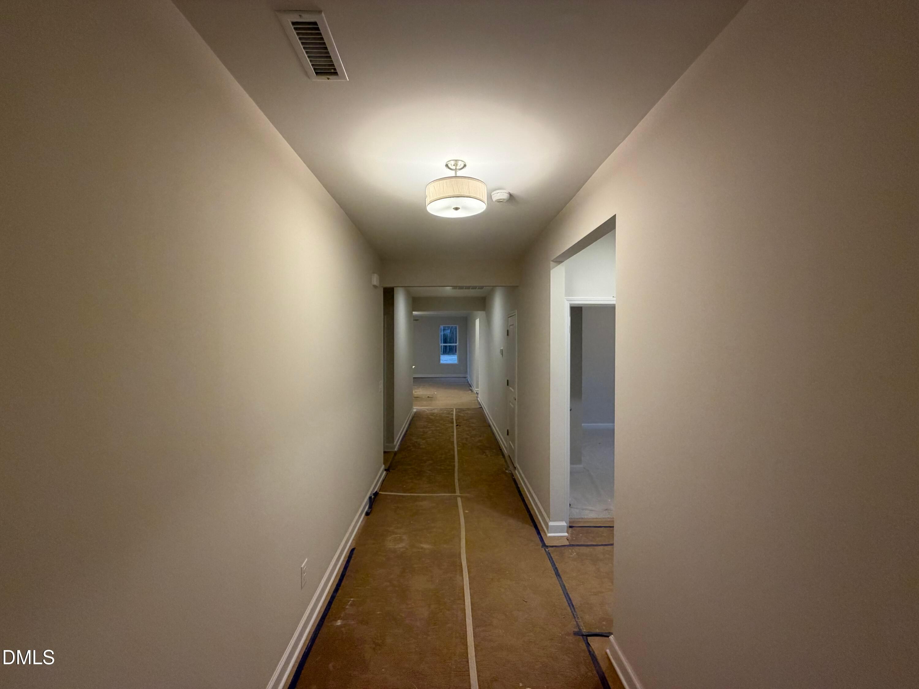 Long hallway with beige walls, pendant lighting, and plywood subfloor in The Daphne C floor plan, Wellers Knoll, Lillington, NC