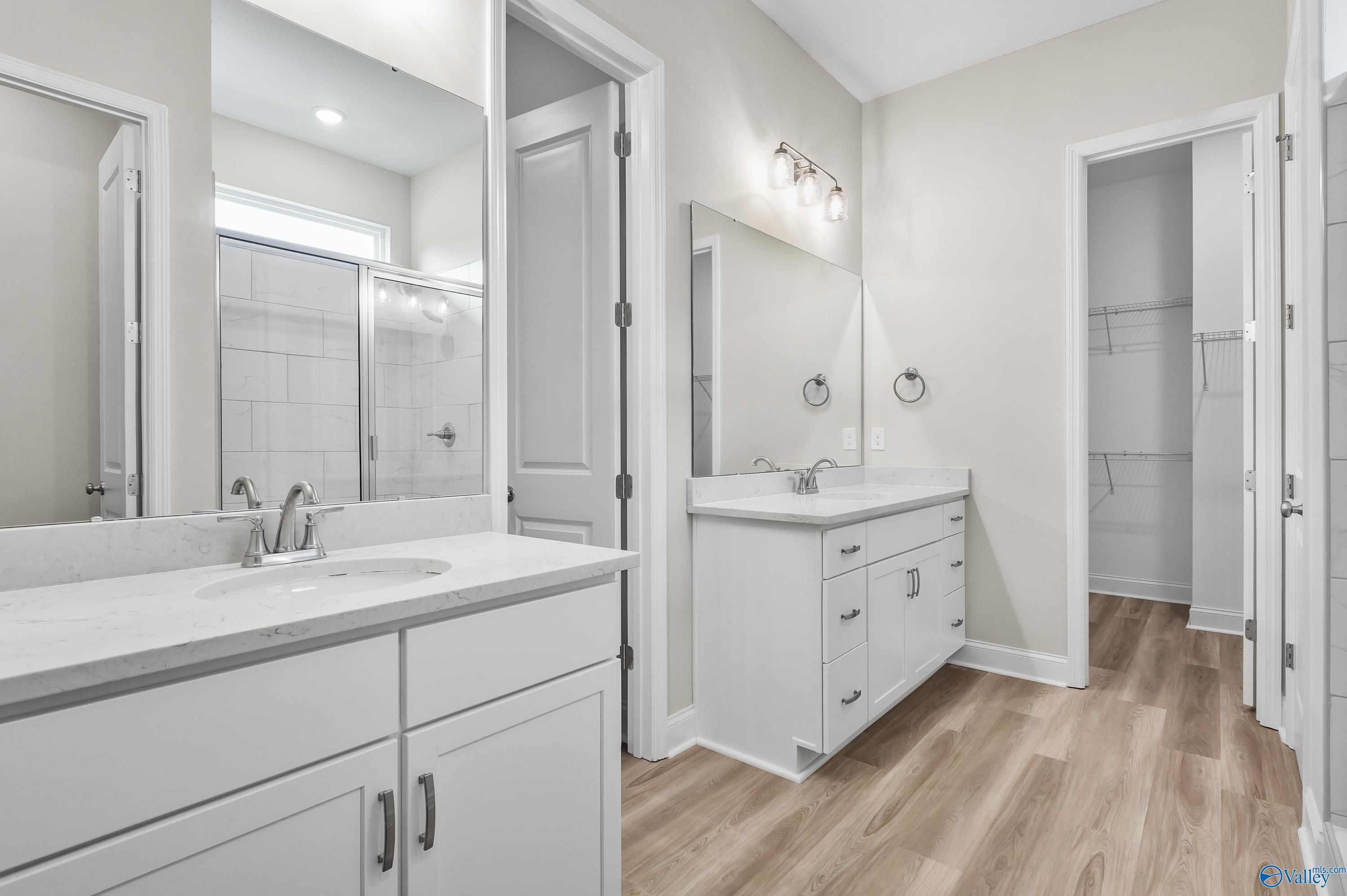 Modern master bathroom with double white vanity, quartz countertop, tiled walk-in shower in Evermore Homes The Haven