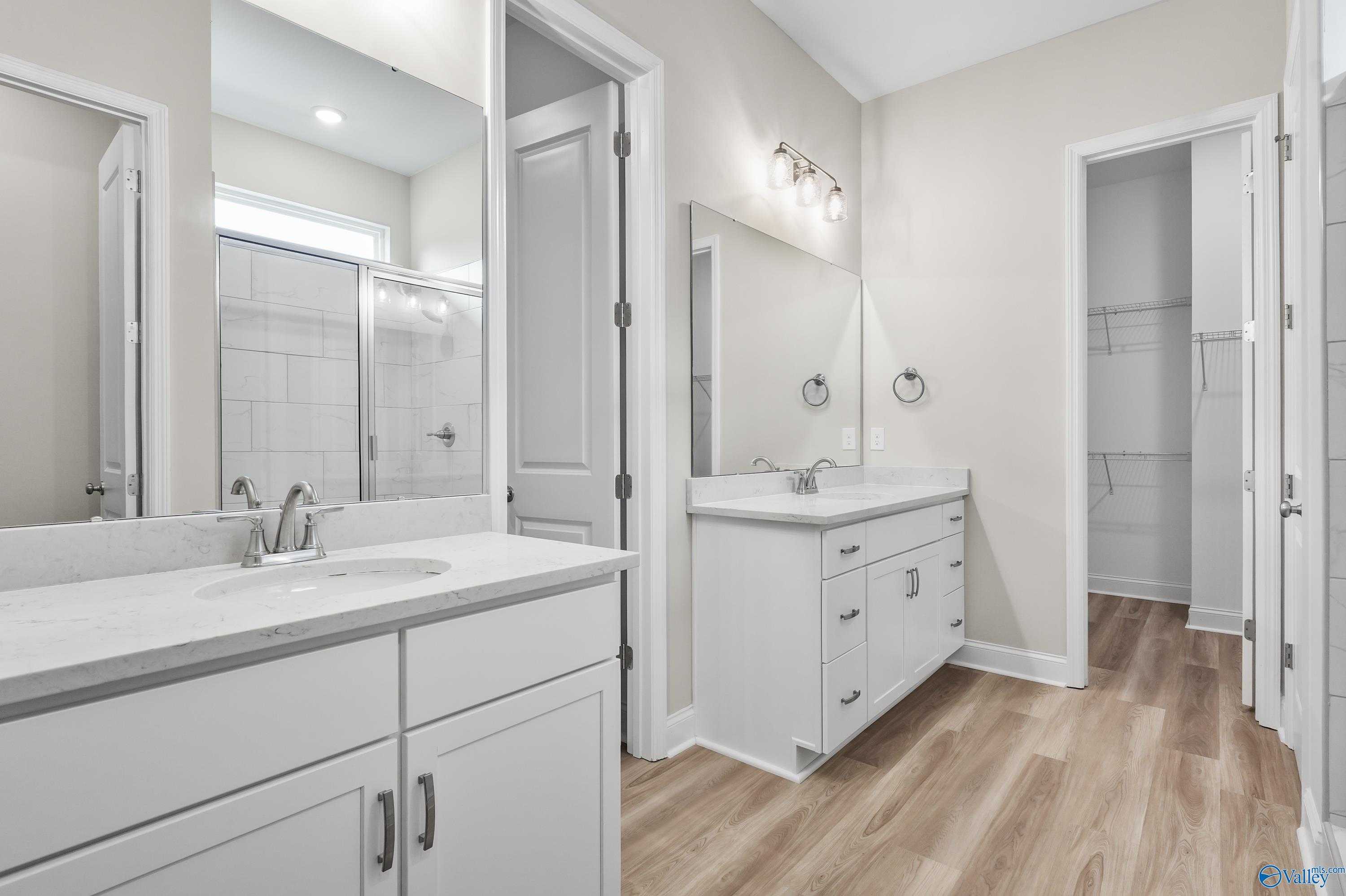 Modern master bathroom with double white vanity, quartz countertop, tiled walk-in shower in Evermore Homes The Haven