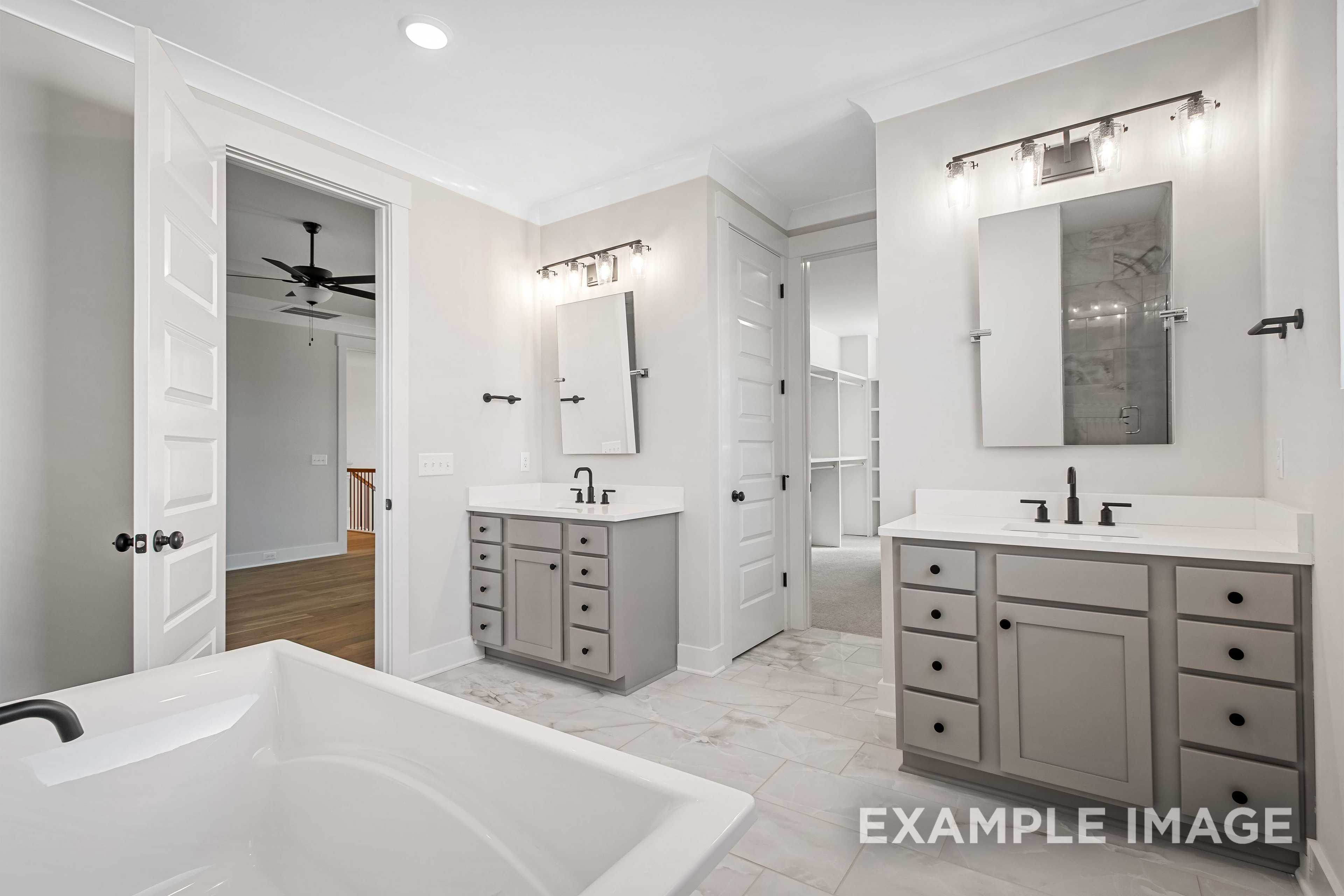 Spacious master bathroom in The Alston A featuring dual gray vanities, freestanding tub, and walk-in shower area