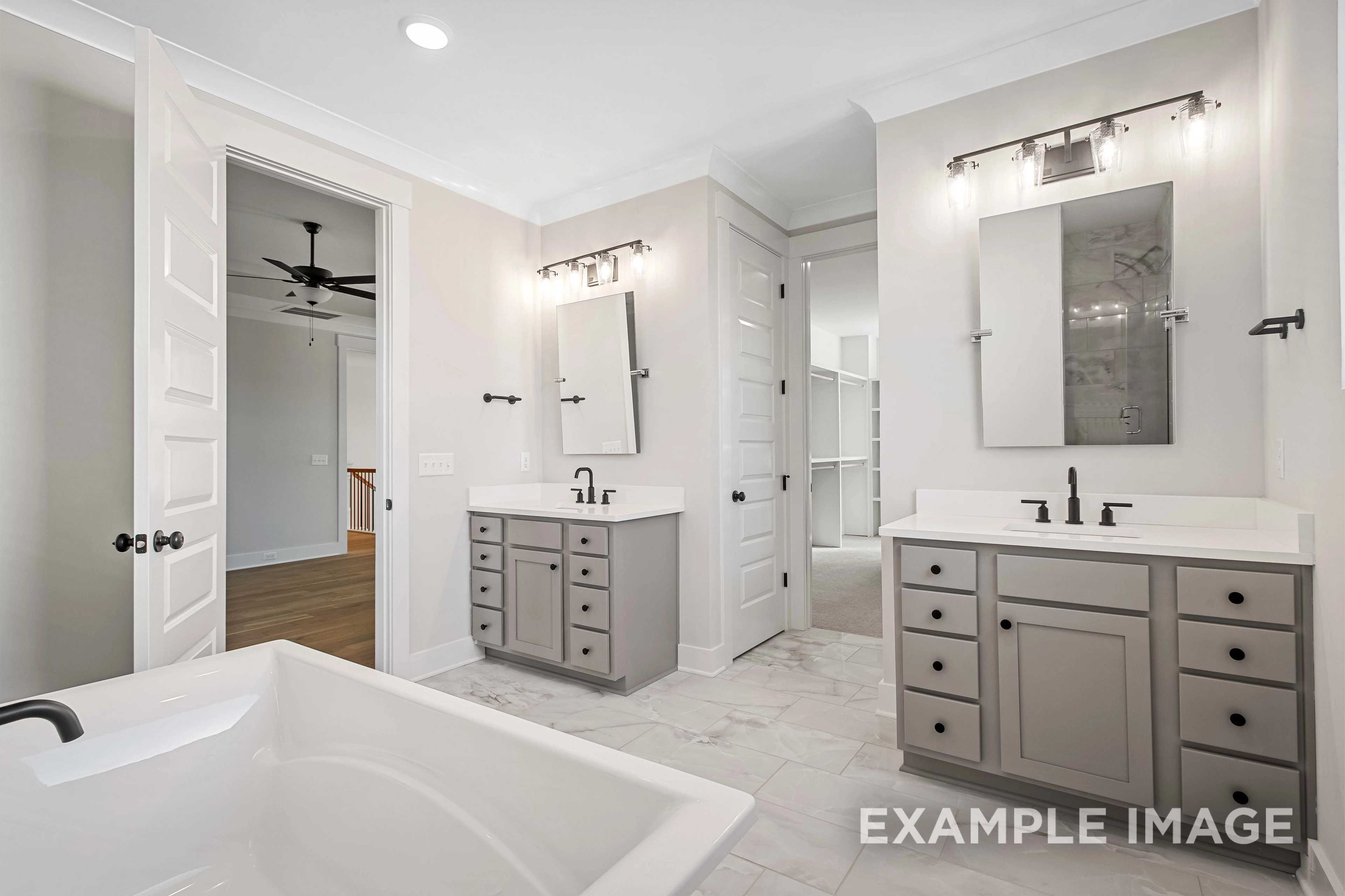 Spacious master bathroom in The Alston A featuring dual gray vanities, freestanding tub, and walk-in shower area