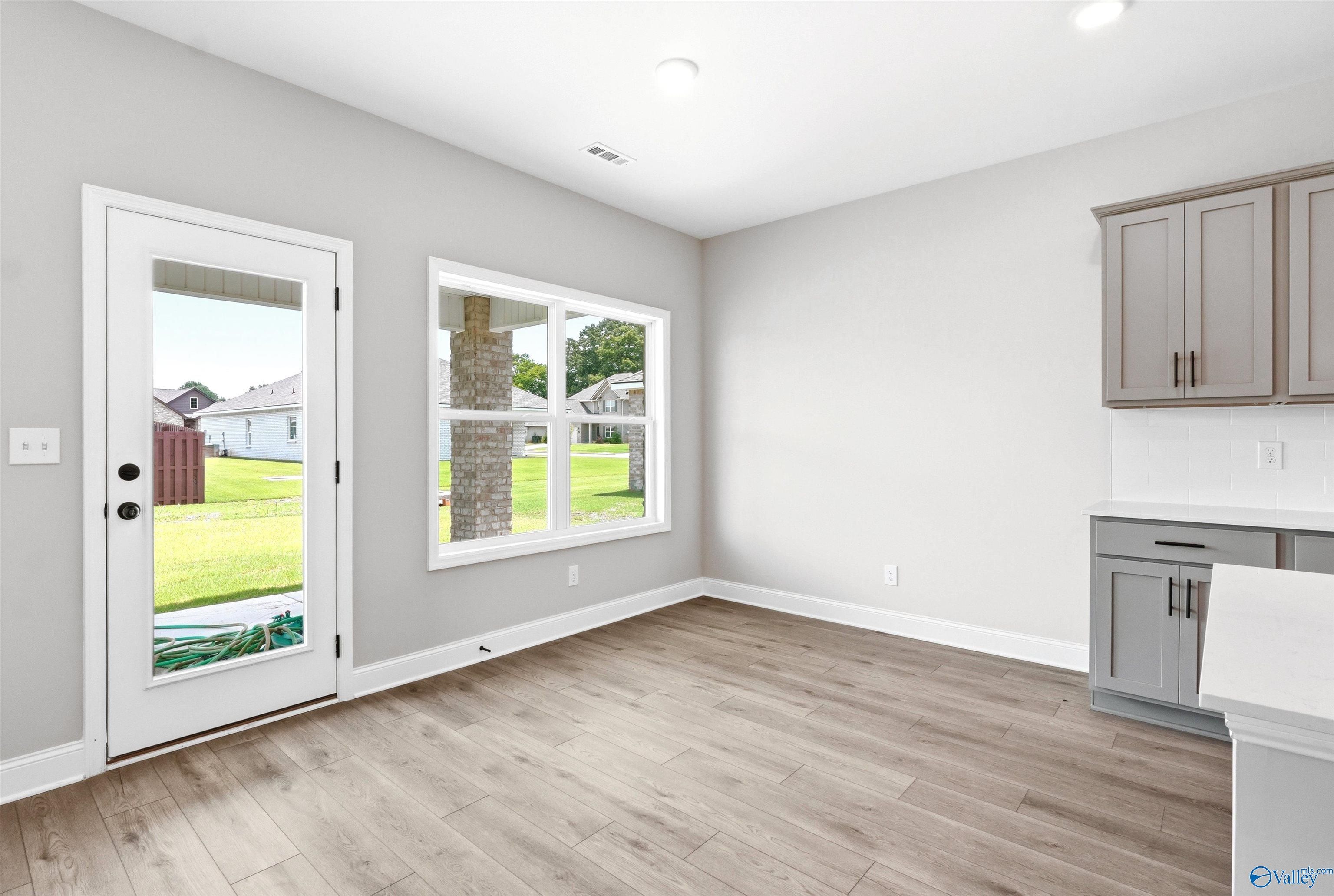 Bright breakfast area with wood-look flooring and backyard access in The Shelby A floor plan at Wood Trail, Toney, Alabama.
