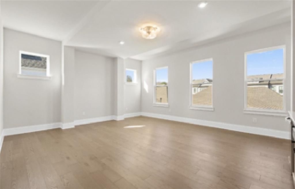 Bright great room with hardwood floors, chandelier, large windows overlooking neighborhood in Davidson Homes The Seaside A, Woodstock, GA