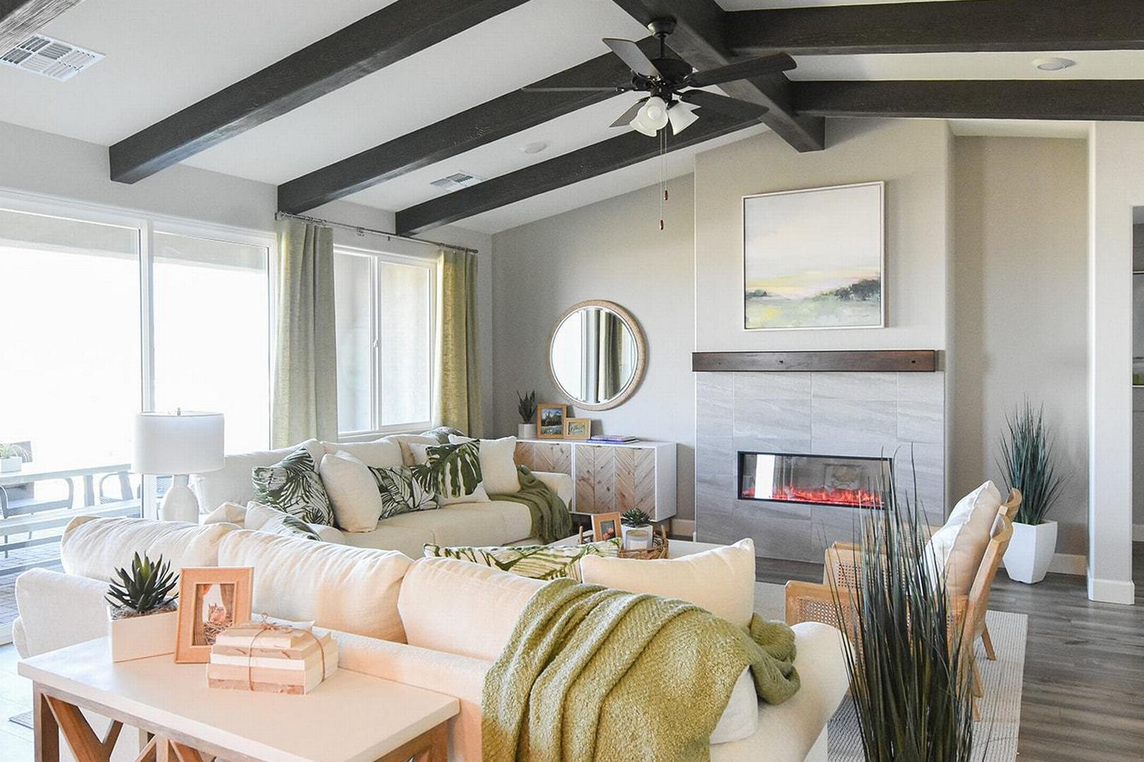 Spacious living room in The Summit E featuring modern gas fireplace, L-shaped white sofa, exposed wood beams, and large windows