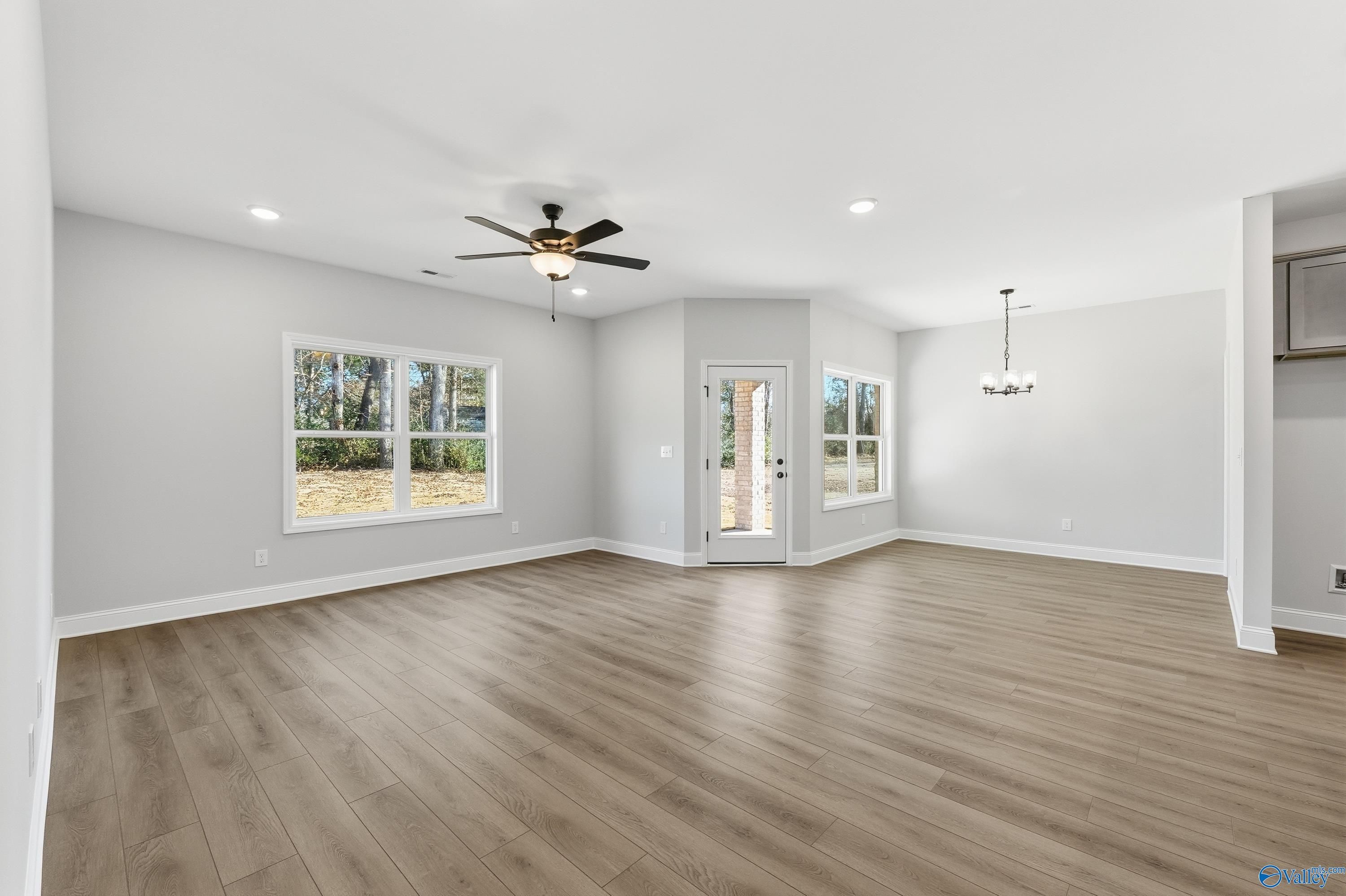 Bright open living room with luxury vinyl plank floors, large windows, ceiling fan in Davidson Homes The Daphne C, New Market, AL