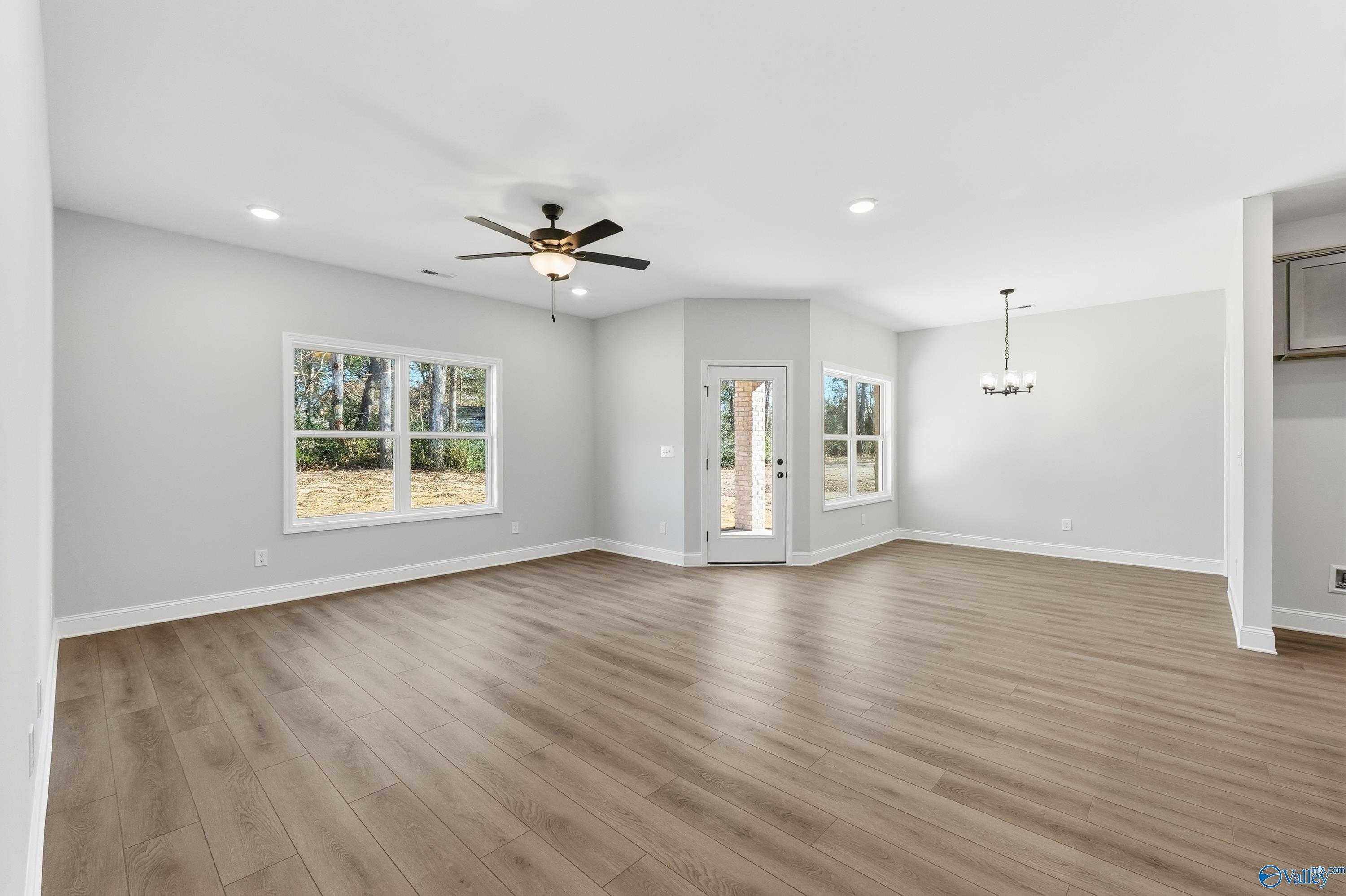 Bright open living room with luxury vinyl plank floors, large windows, ceiling fan in Davidson Homes The Daphne C, New Market, AL