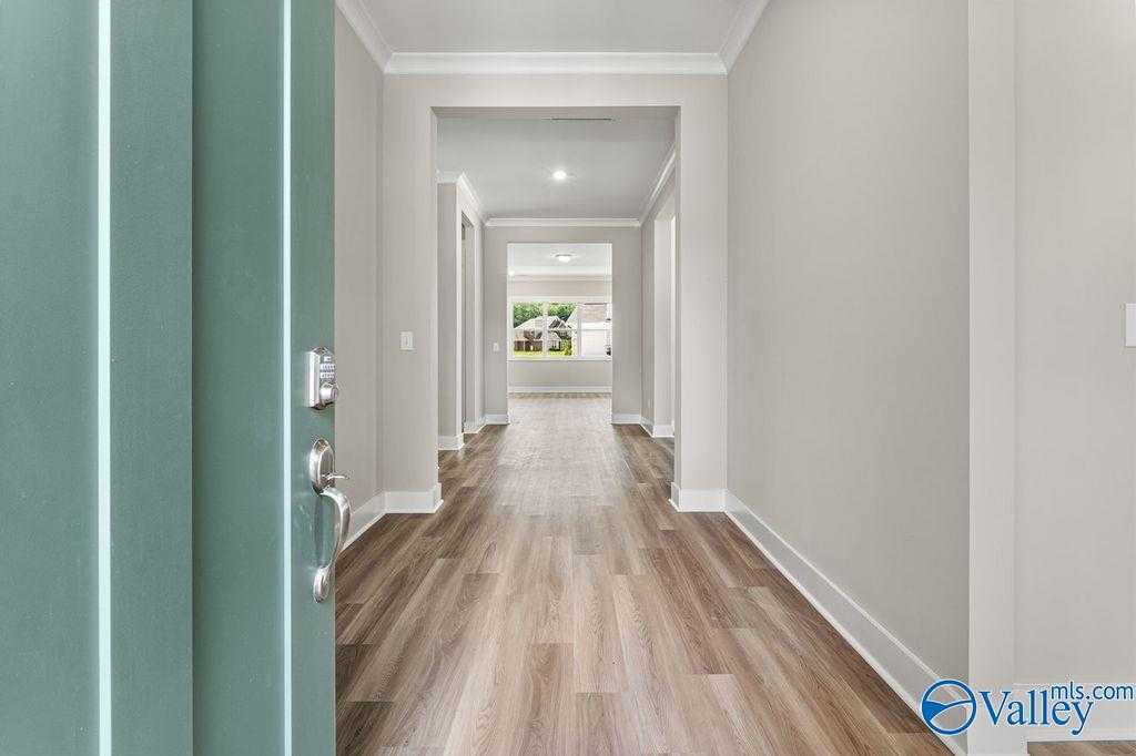 Welcoming entry hallway with luxury vinyl plank floors, white walls, and open layout in Evermore Homes The Oxford, Owens Cross Roads, AL