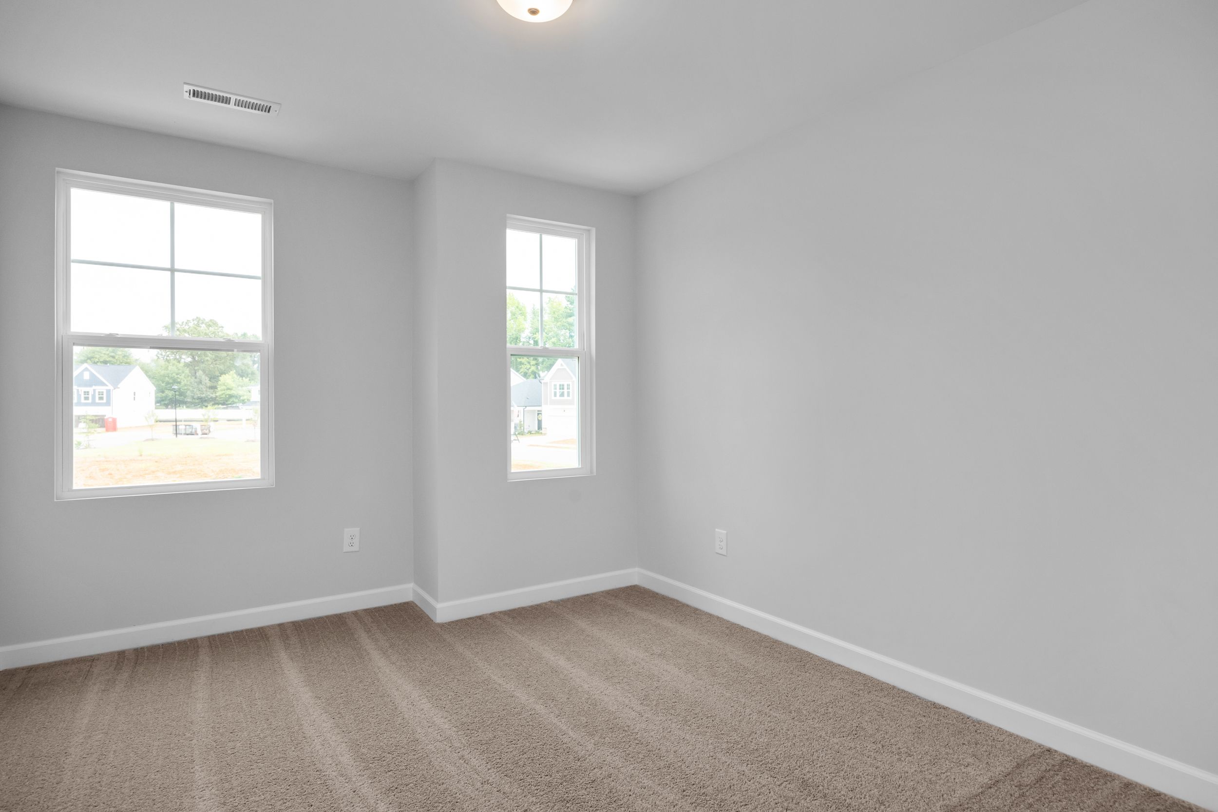 Bright, carpeted bedroom in The Durham home design by Davidson Homes featuring neutral walls and natural light.