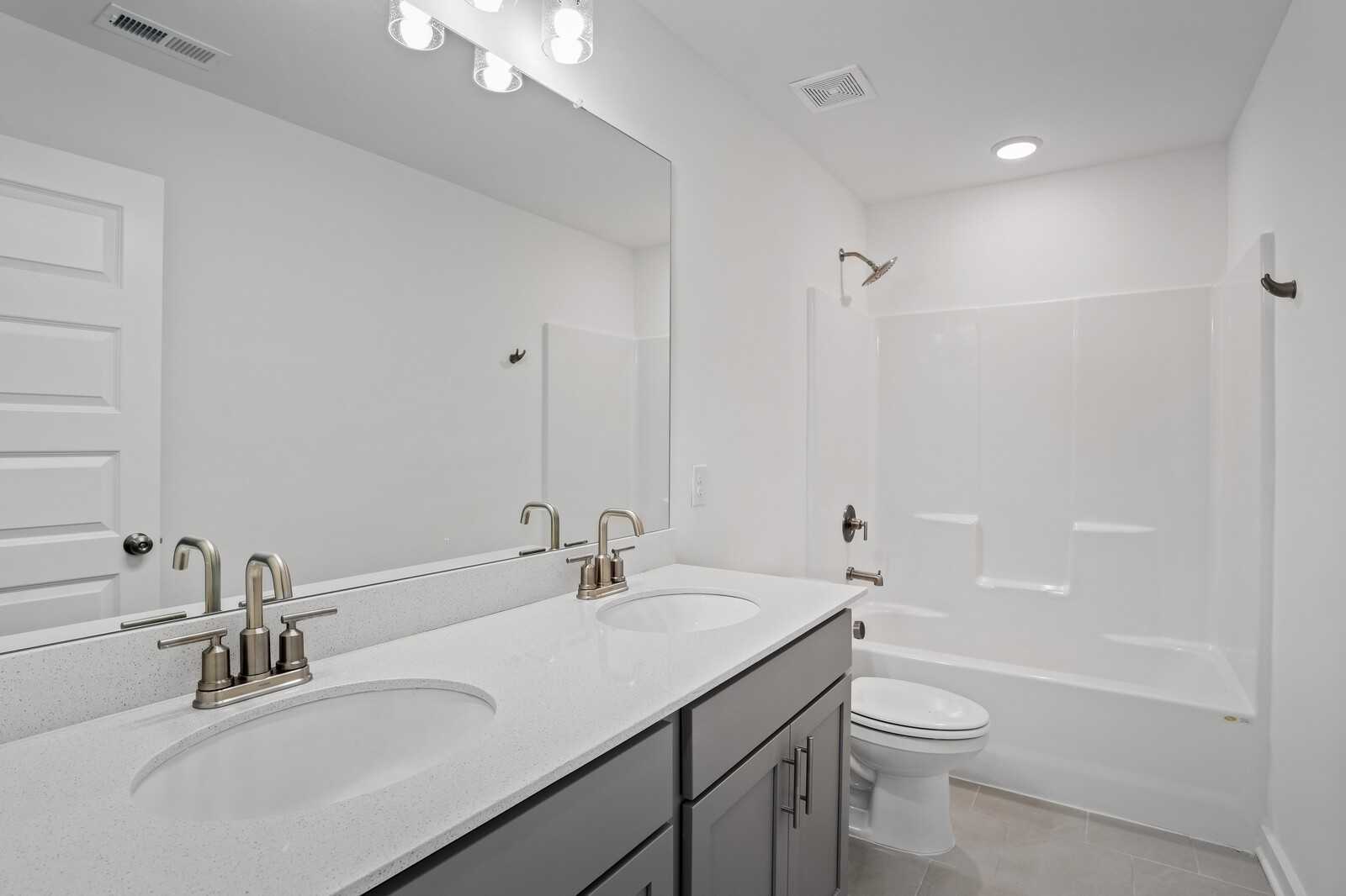 Modern double-sink vanity with quartz countertop and soaking tub in Davidson Homes The Logan B bathroom, White House, TN