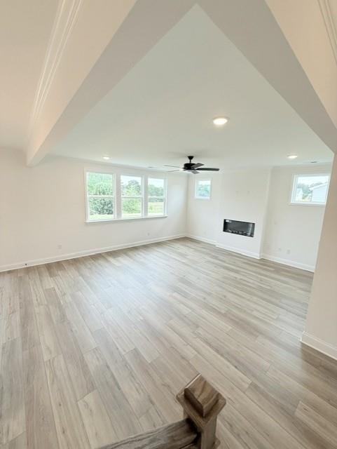 Spacious living room with modern fireplace and wood-look flooring in The Hickory B floor plan at Wehunt Meadows, Hoschton.