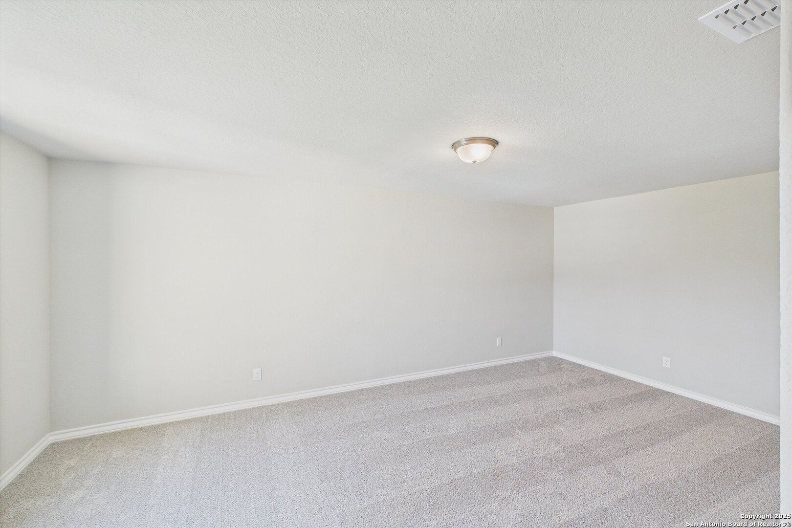 Spacious empty bedroom with neutral beige walls, carpeted floor, and ceiling light in Davidson Homes The Jennings H, Ladera, San Antonio