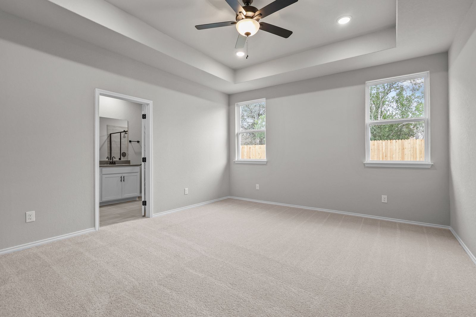 Spacious master suite with tray ceiling, carpeted flooring, and ensuite bathroom in The Glenwood by Davidson Homes.