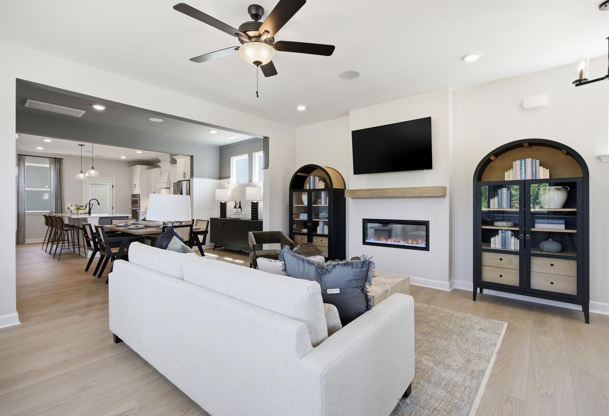 Open-concept living room in The Burke C featuring a modern fireplace, stylish shelving, and views of the dining area.