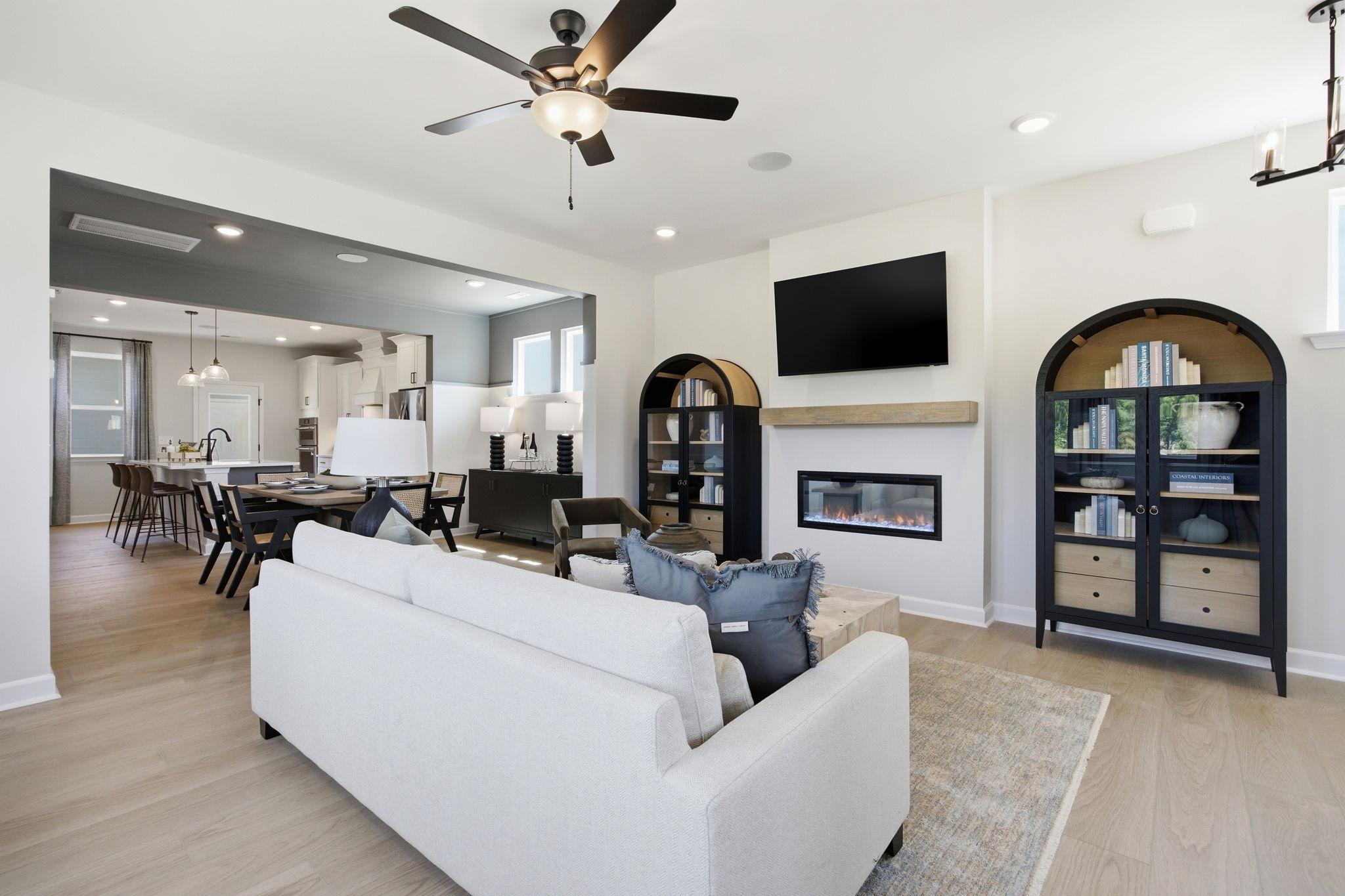 Open-concept living room in The Burke C featuring a modern fireplace, stylish shelving, and views of the dining area.