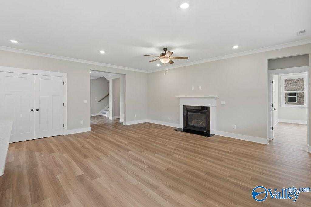 Spacious living room with gas fireplace, ceiling fan, and open layout in Evermore Homes The Oxford, Owens Cross Roads, AL