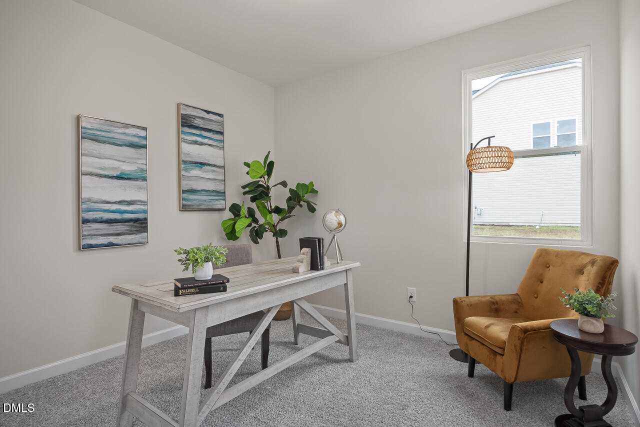 Cozy home office with farmhouse desk, fiddle leaf fig, abstract blue art, rattan lamp, and orange velvet armchair in Davidson Homes The Carter C, Lillington, NC