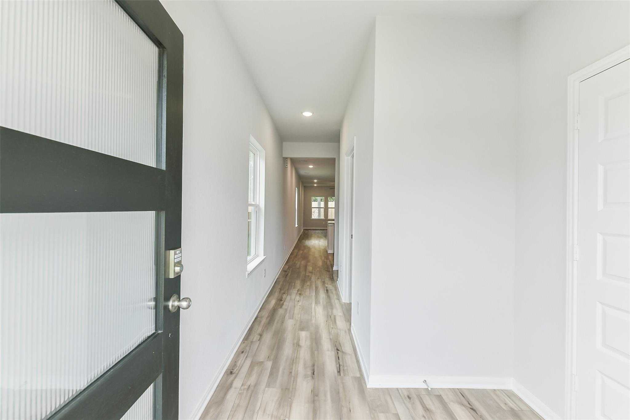 Bright entry hallway with modern frosted glass door, hardwood floors in Davidson Homes The Sabine F, Conroe Texas