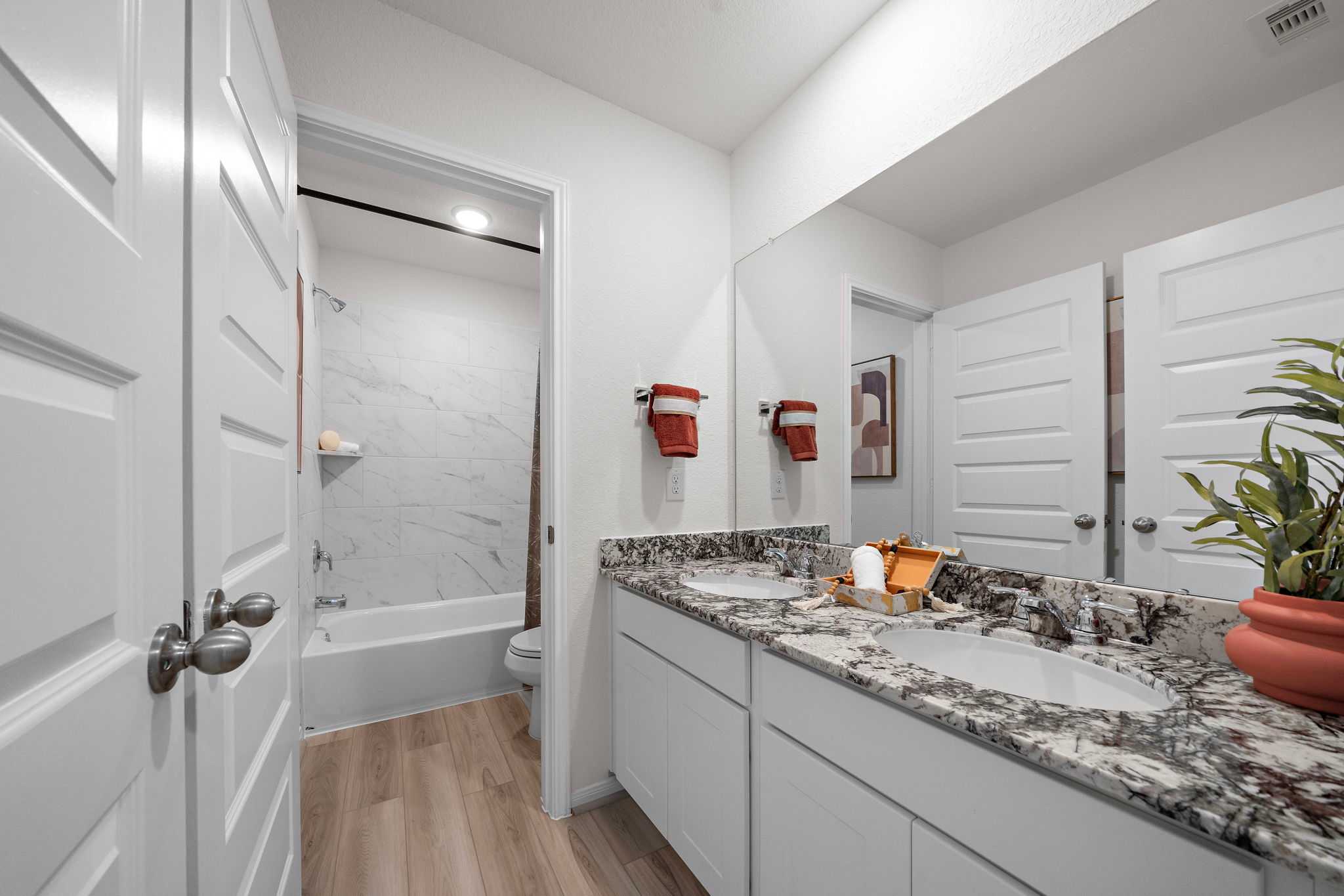 Spacious primary bathroom at The Villages at WestPointe in Dayton Texas with double granite vanity, soaking tub, and hardwood floors